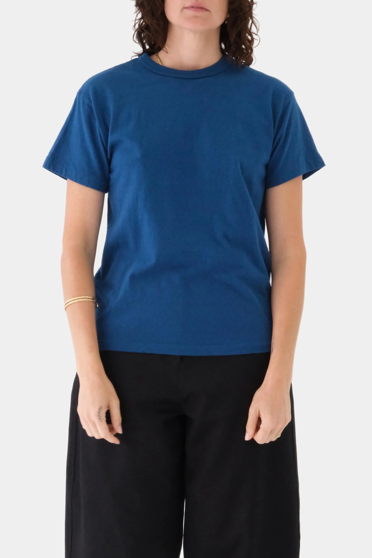 Person wearing a blue t-shirt and black pants on a white background