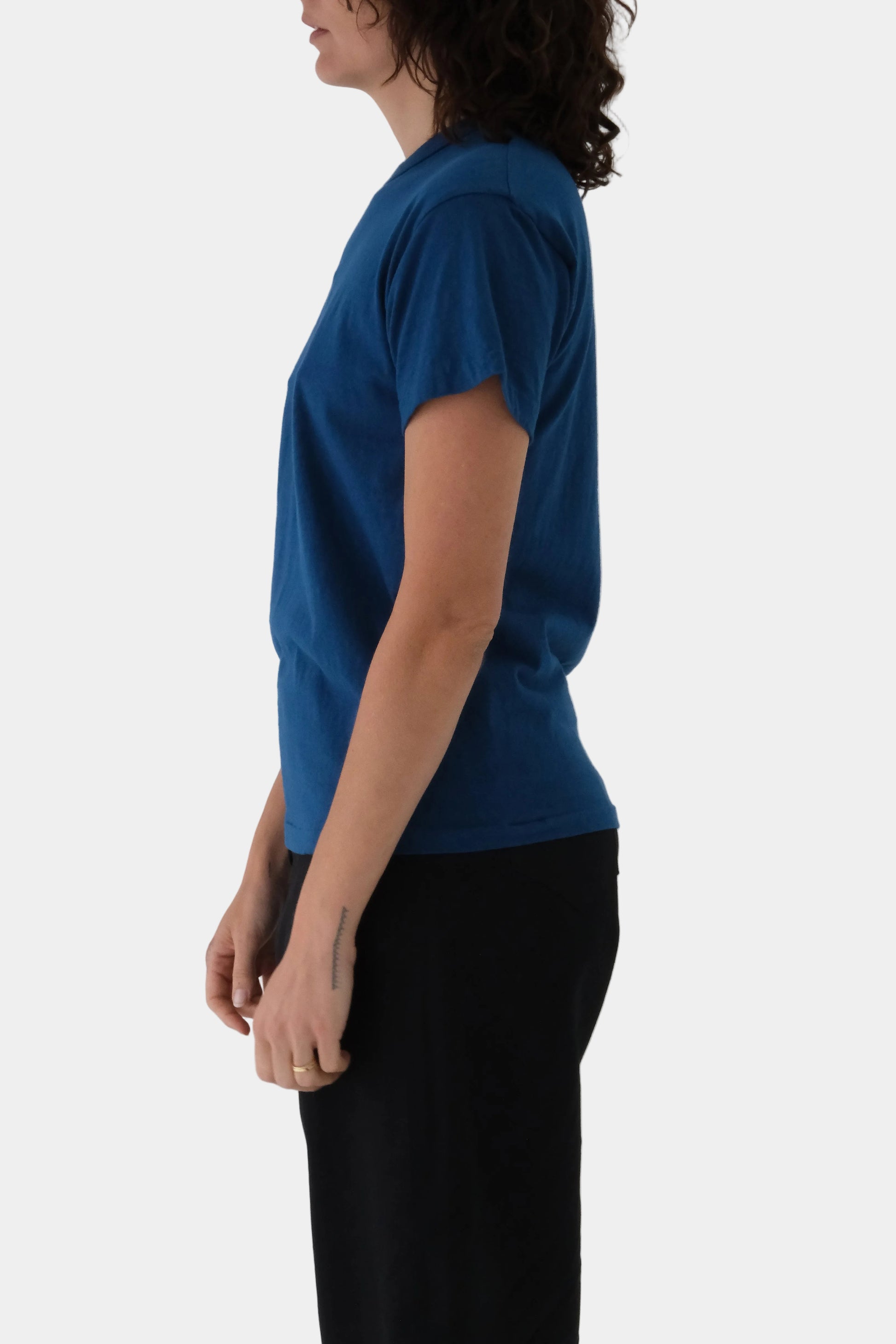 Person wearing a blue t-shirt and black pants on a light gray background
