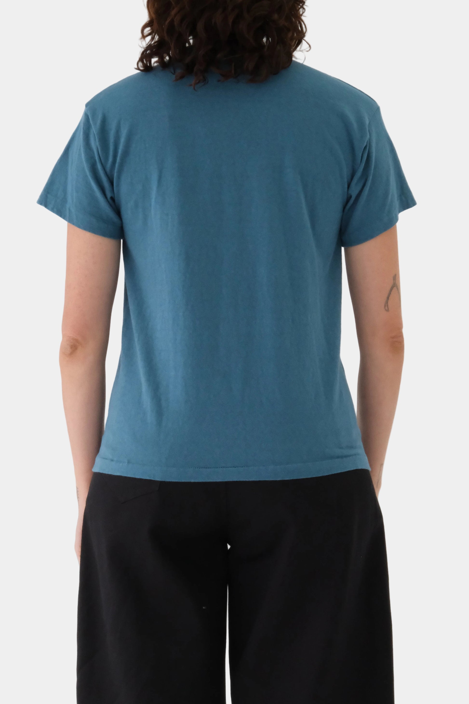 Person wearing a Sunday t-shirt in dragonfly and black pants on a white background