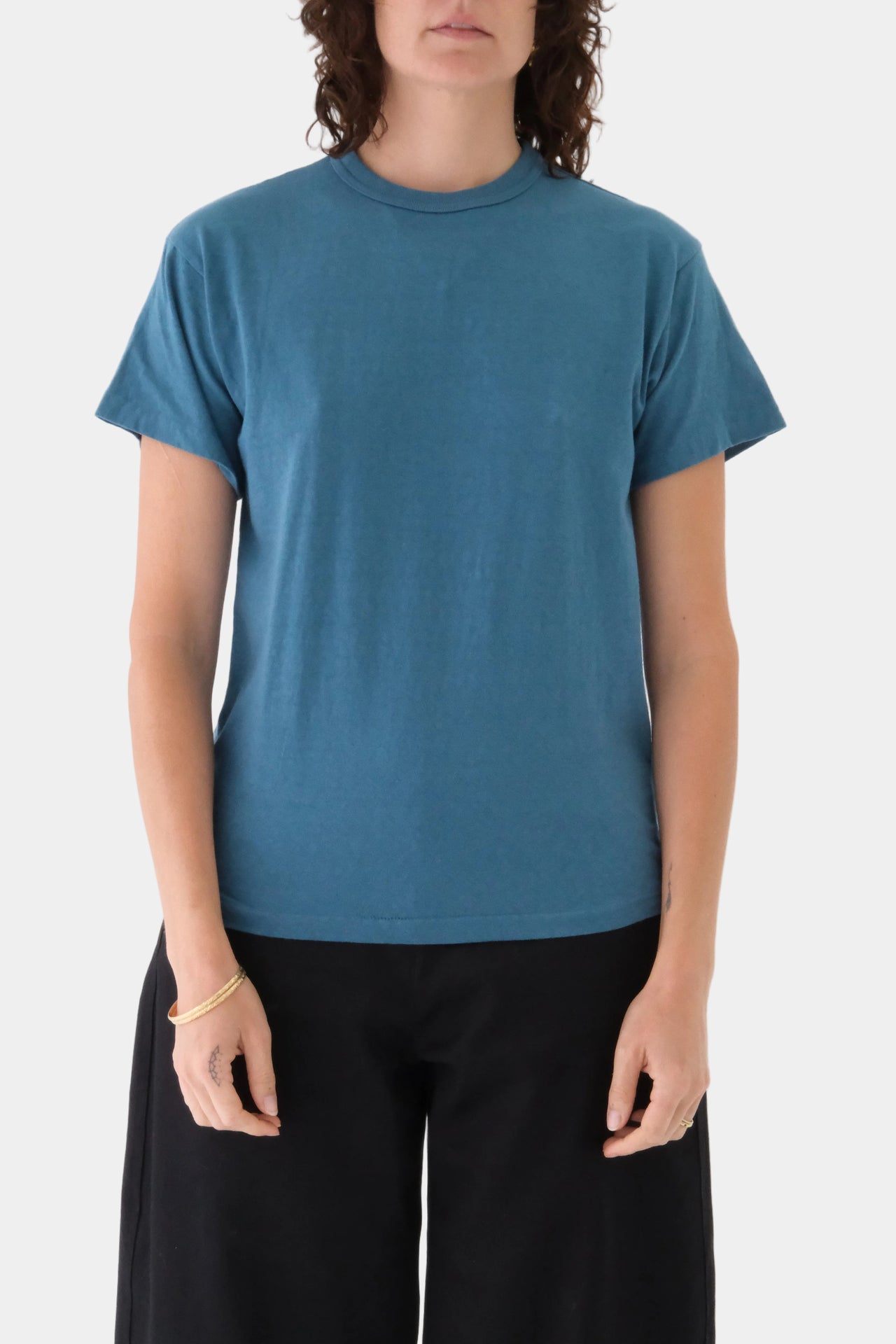 Person wearing a blue t-shirt and black pants on a white background