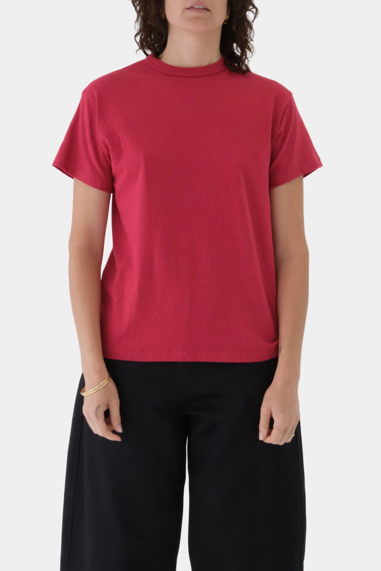 Person wearing a red t-shirt and black pants on a plain background