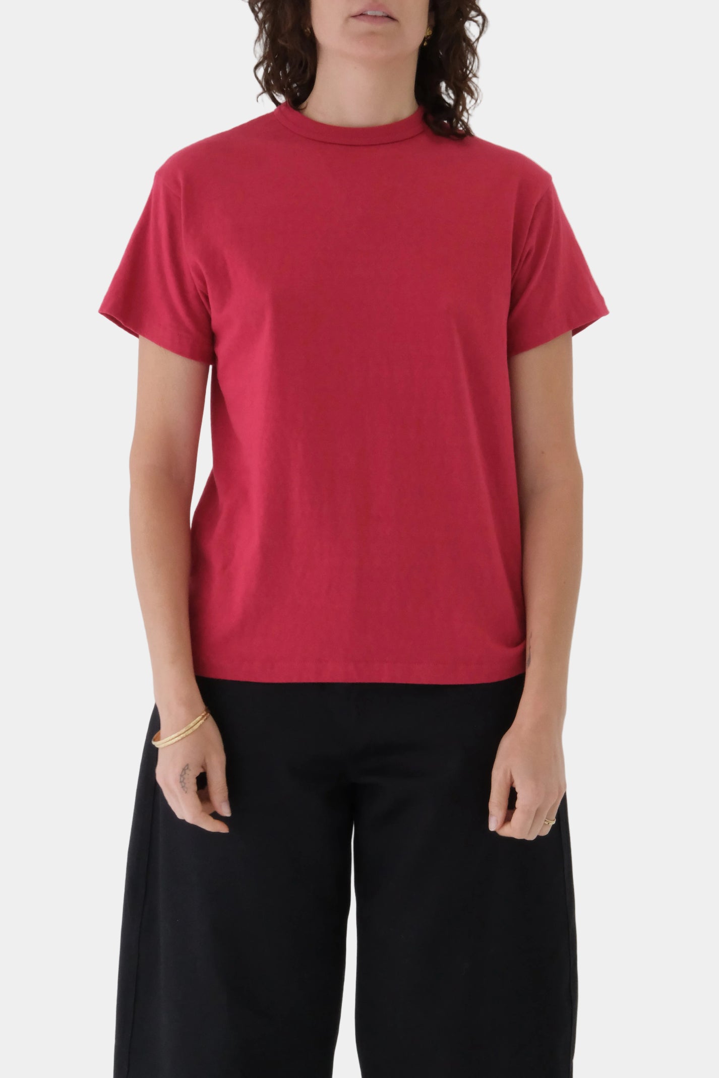 Person wearing a red t-shirt and black pants on a plain background