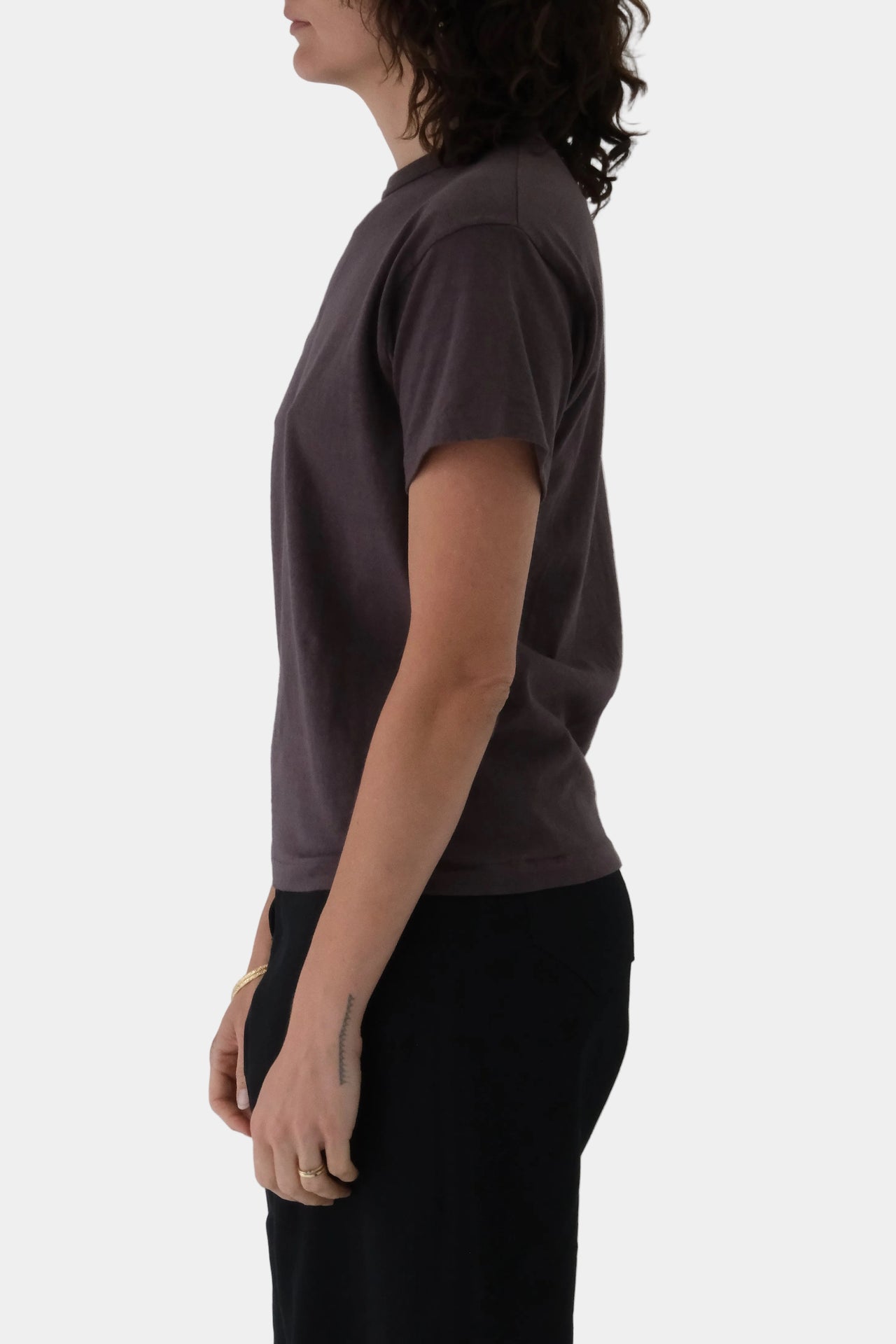 Person wearing a plain brown t-shirt and black pants on a white background
