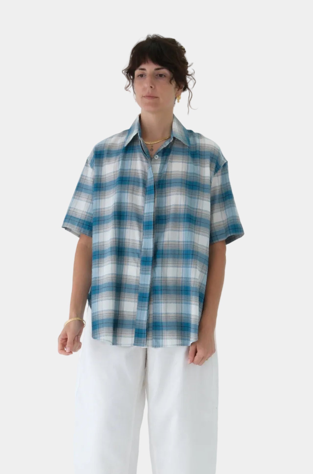 Person wearing a blue and white checkered shirt with white pants on a light gray background