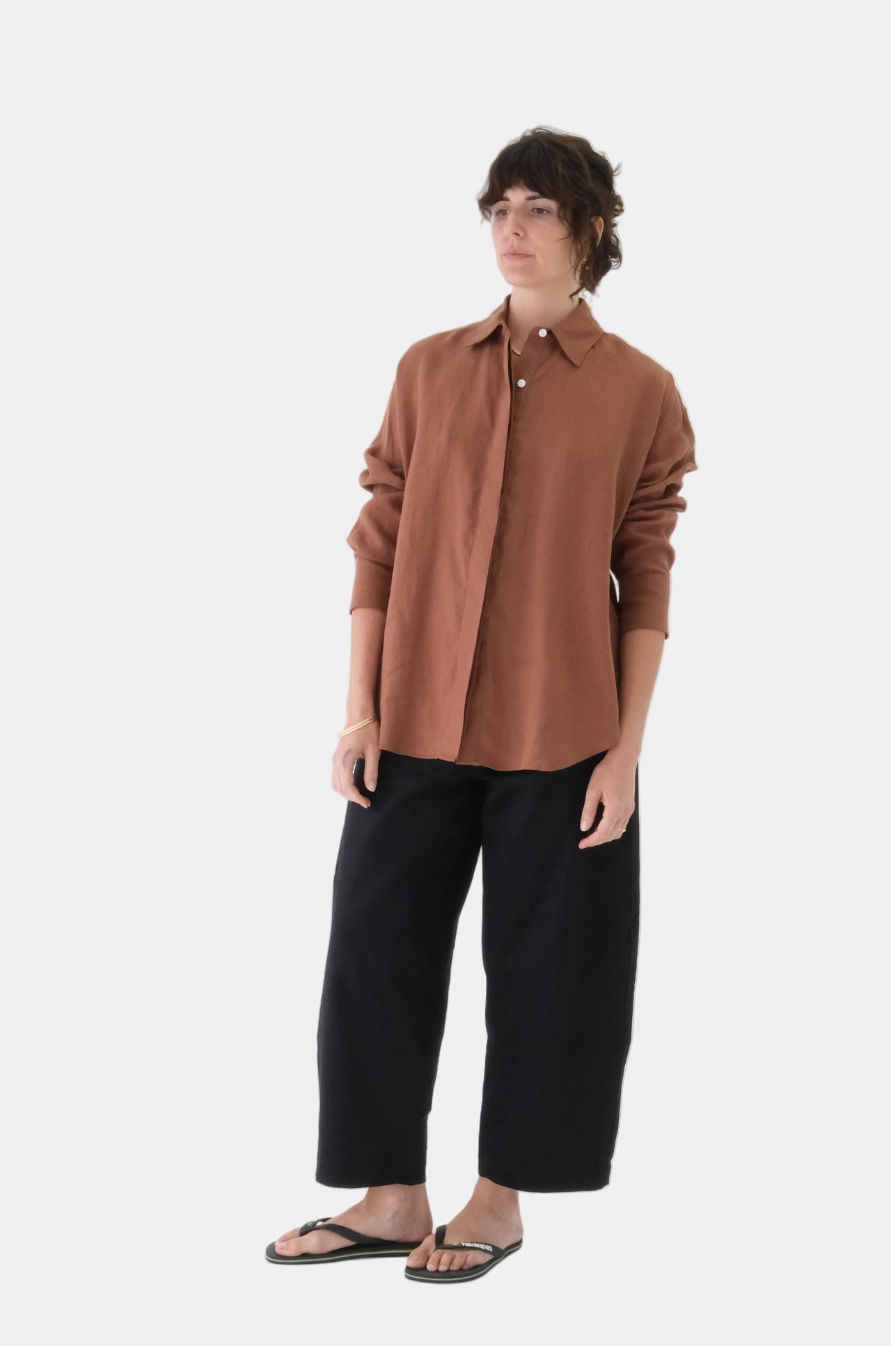 Person wearing a brown shirt and black pants on a white background