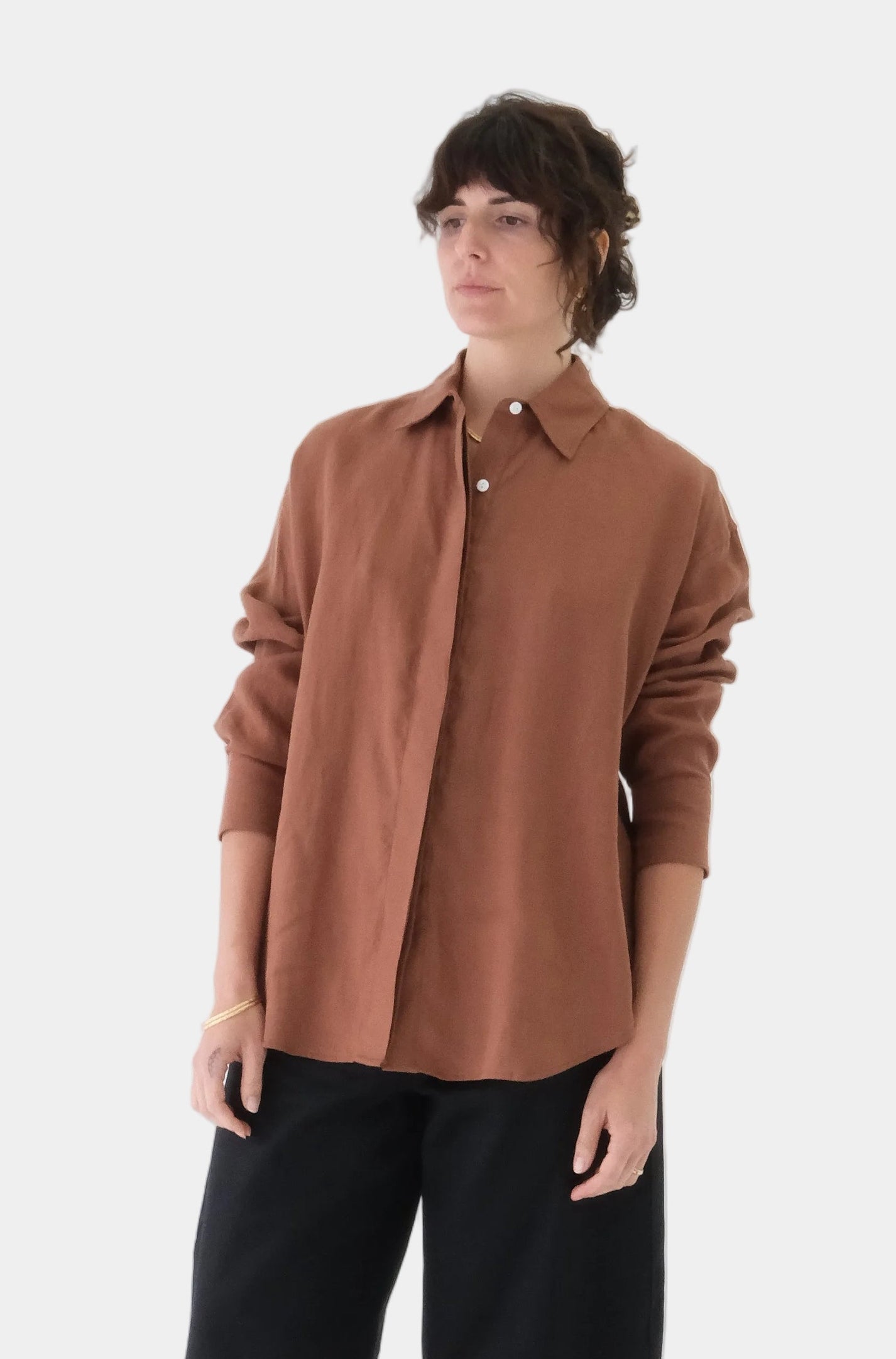 Person wearing a brown shirt and black pants on a white background