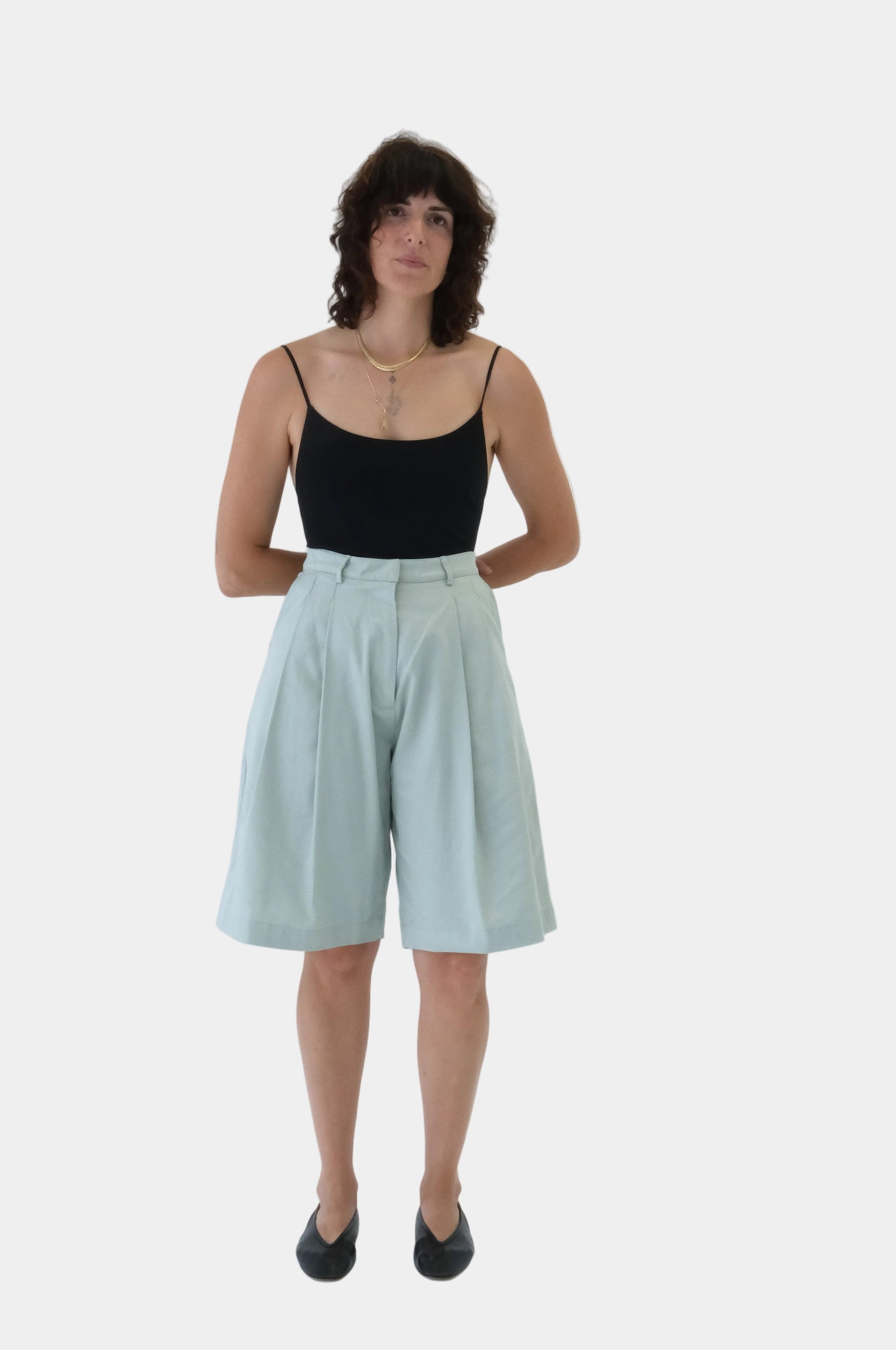 Woman wearing a black top and light green shorts on a white background