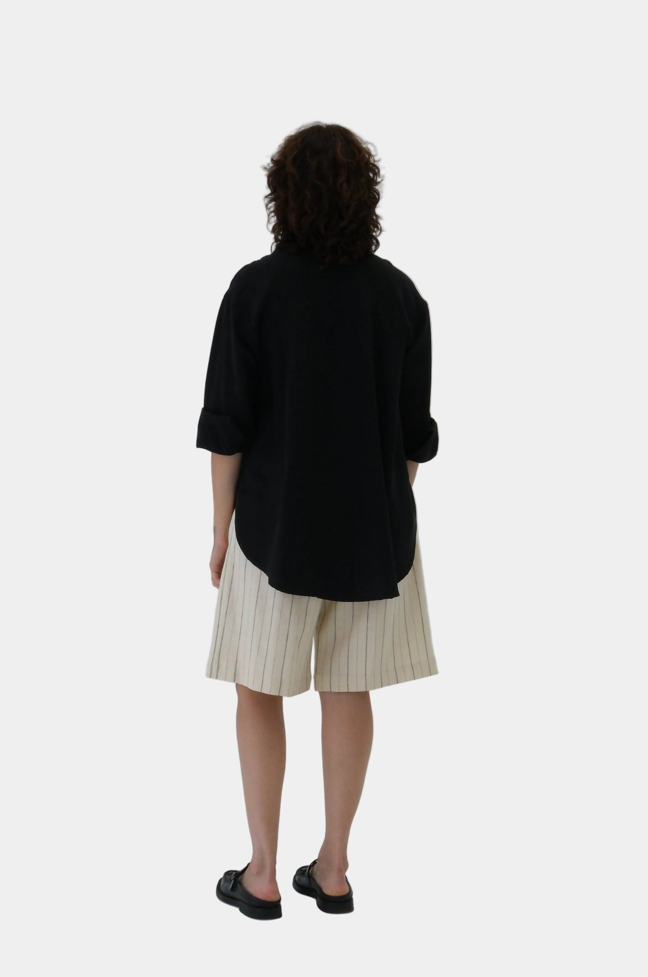 Woman wearing a black top and cream skirt on a white background