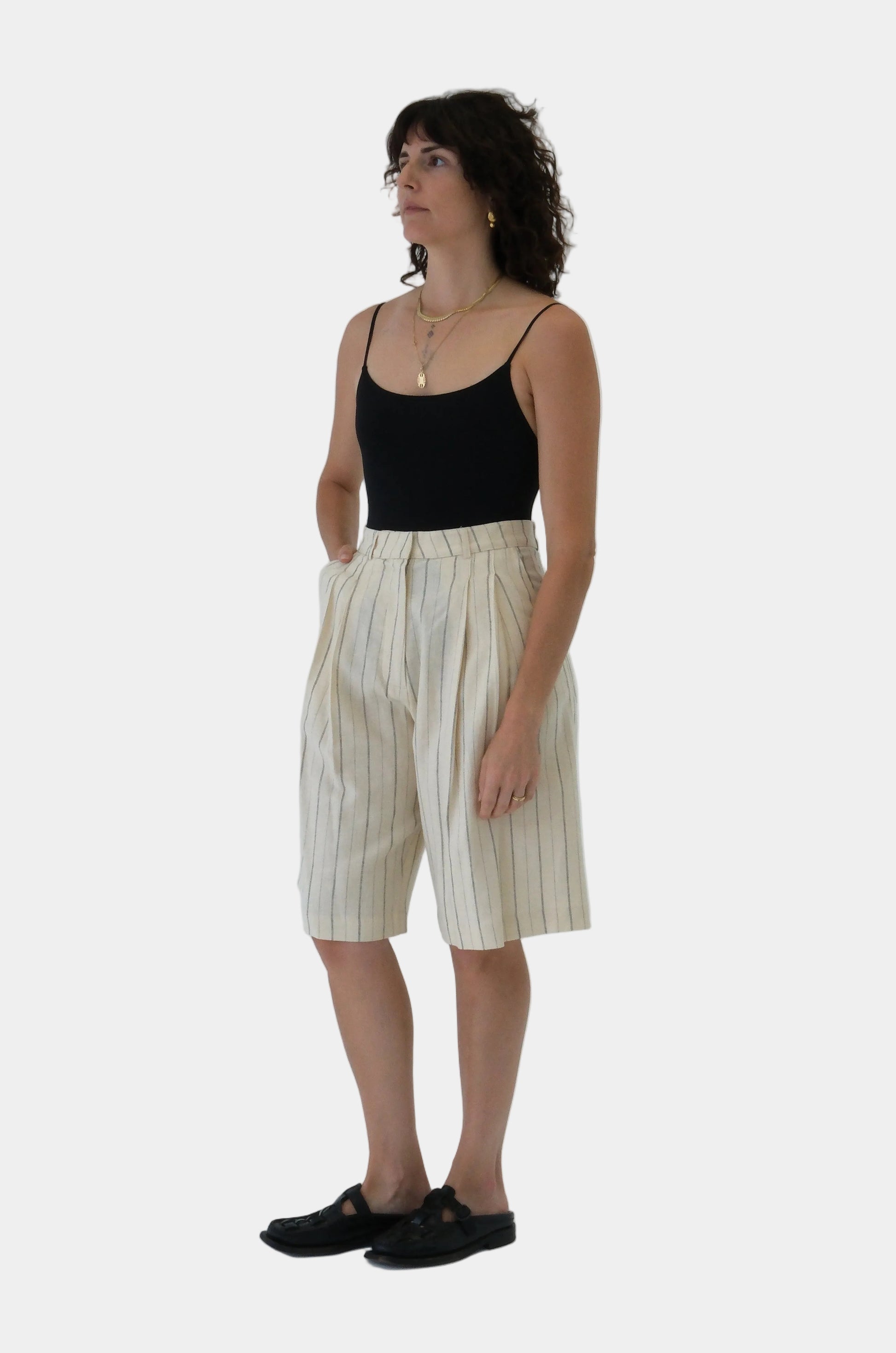 Woman wearing a black top and beige striped pants on a white background