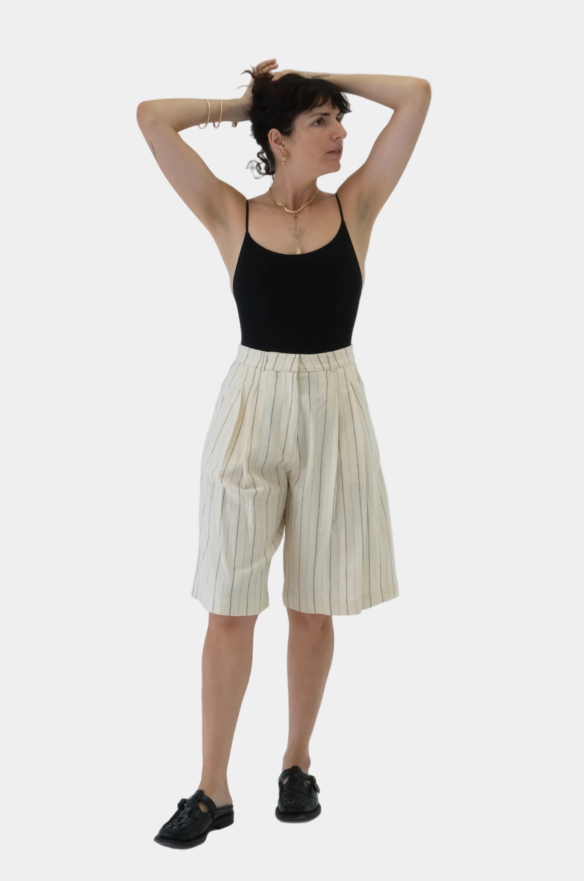 Person wearing a black top and striped shorts on a white background