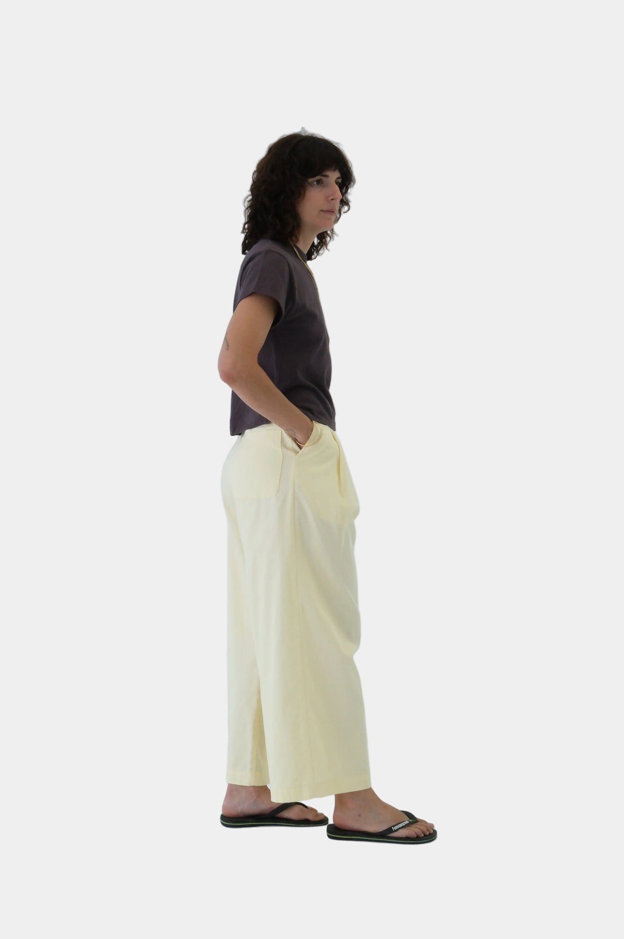 Person wearing a dark shirt and light yellow pants on a white background