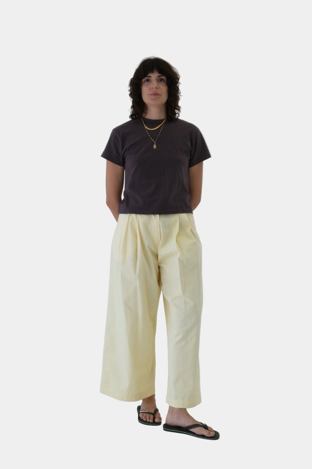 Person wearing a dark shirt and light yellow pants on a white background