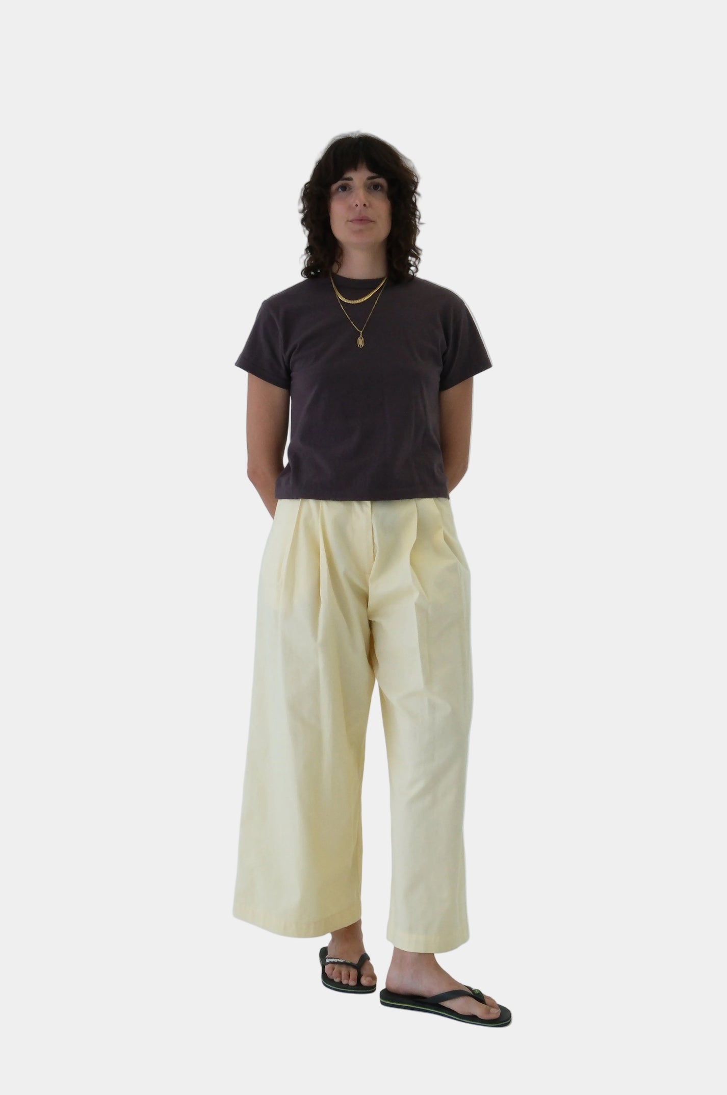 Person wearing a dark shirt and light yellow pants on a white background