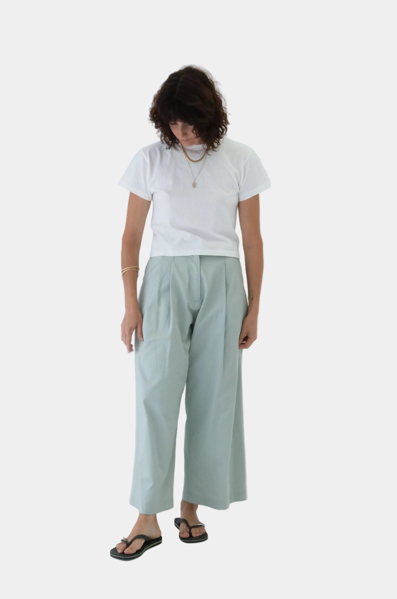 Person wearing a white t-shirt and light green pants on a white background
