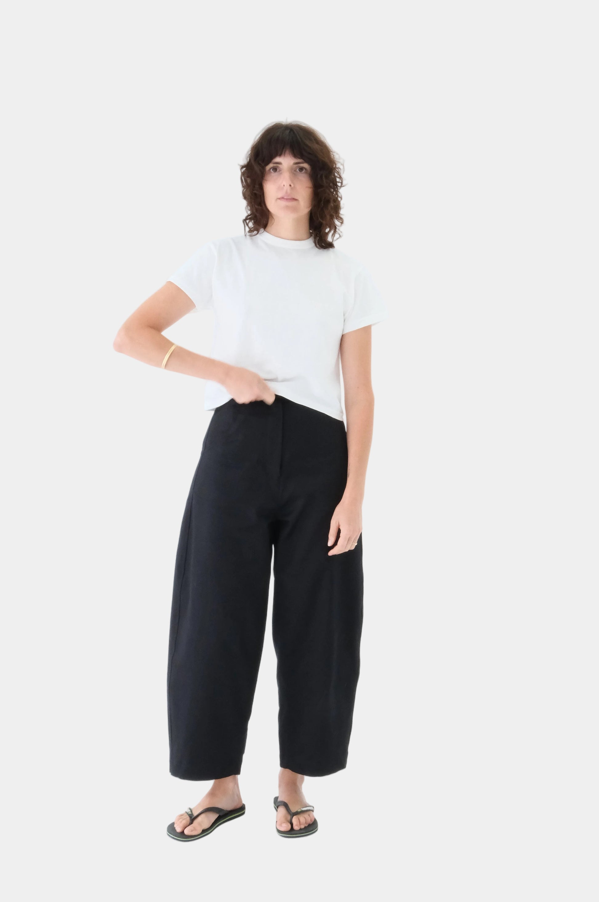 Person wearing a white t-shirt and black pants on a white background