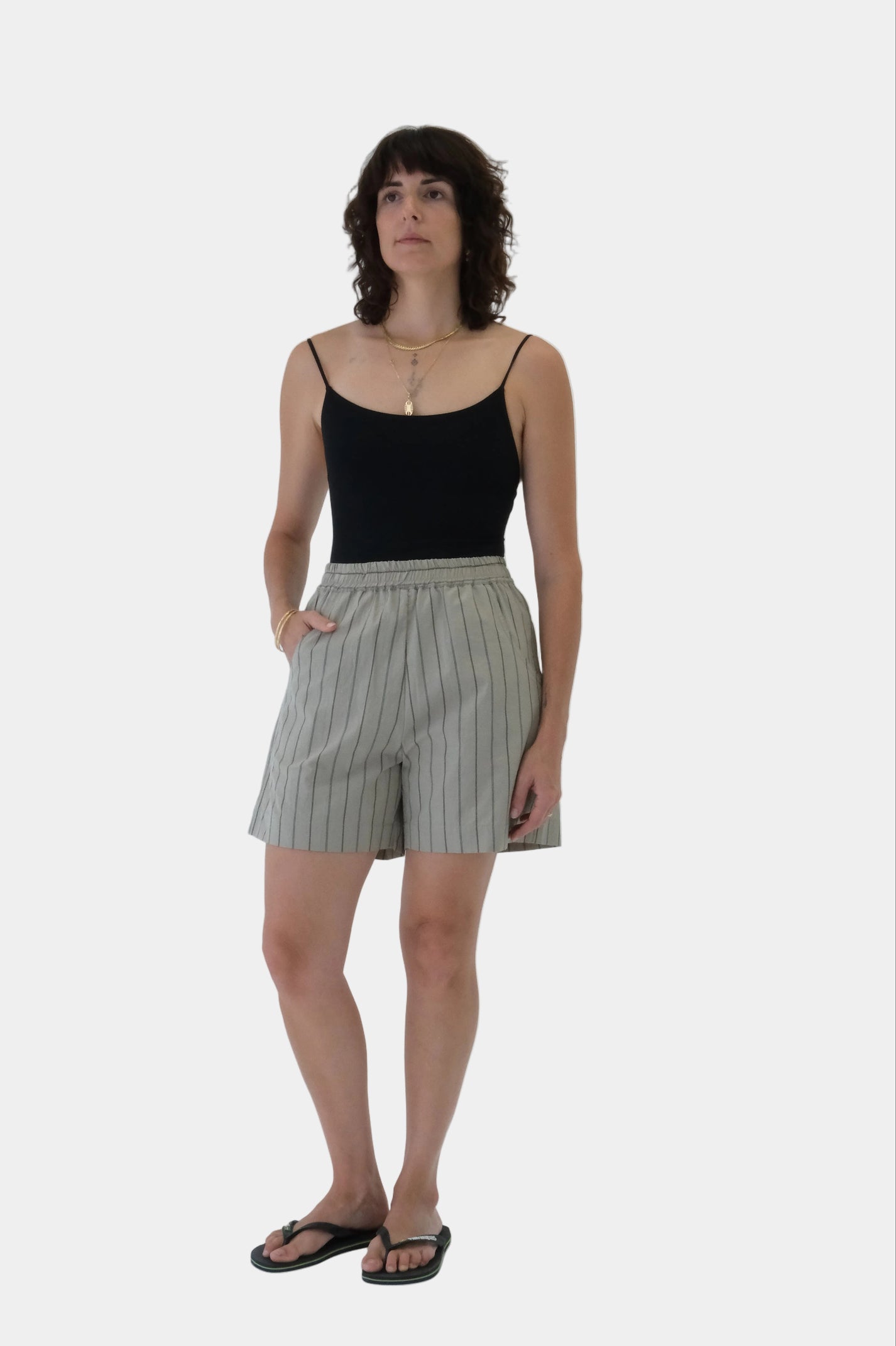 Woman wearing a black tank top and striped shorts on a white background