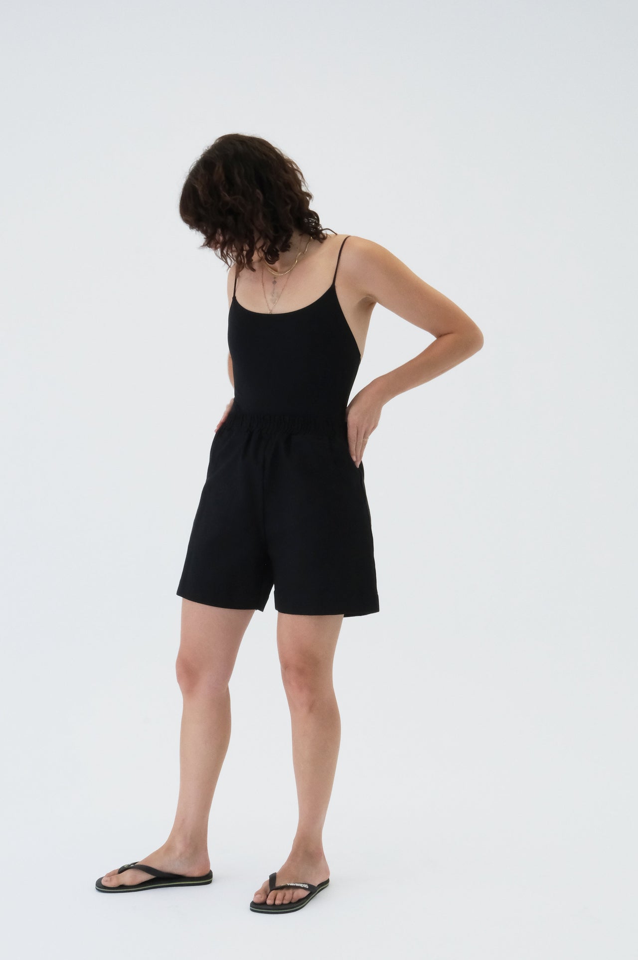 Person wearing a black sleeveless top and shorts on a white background