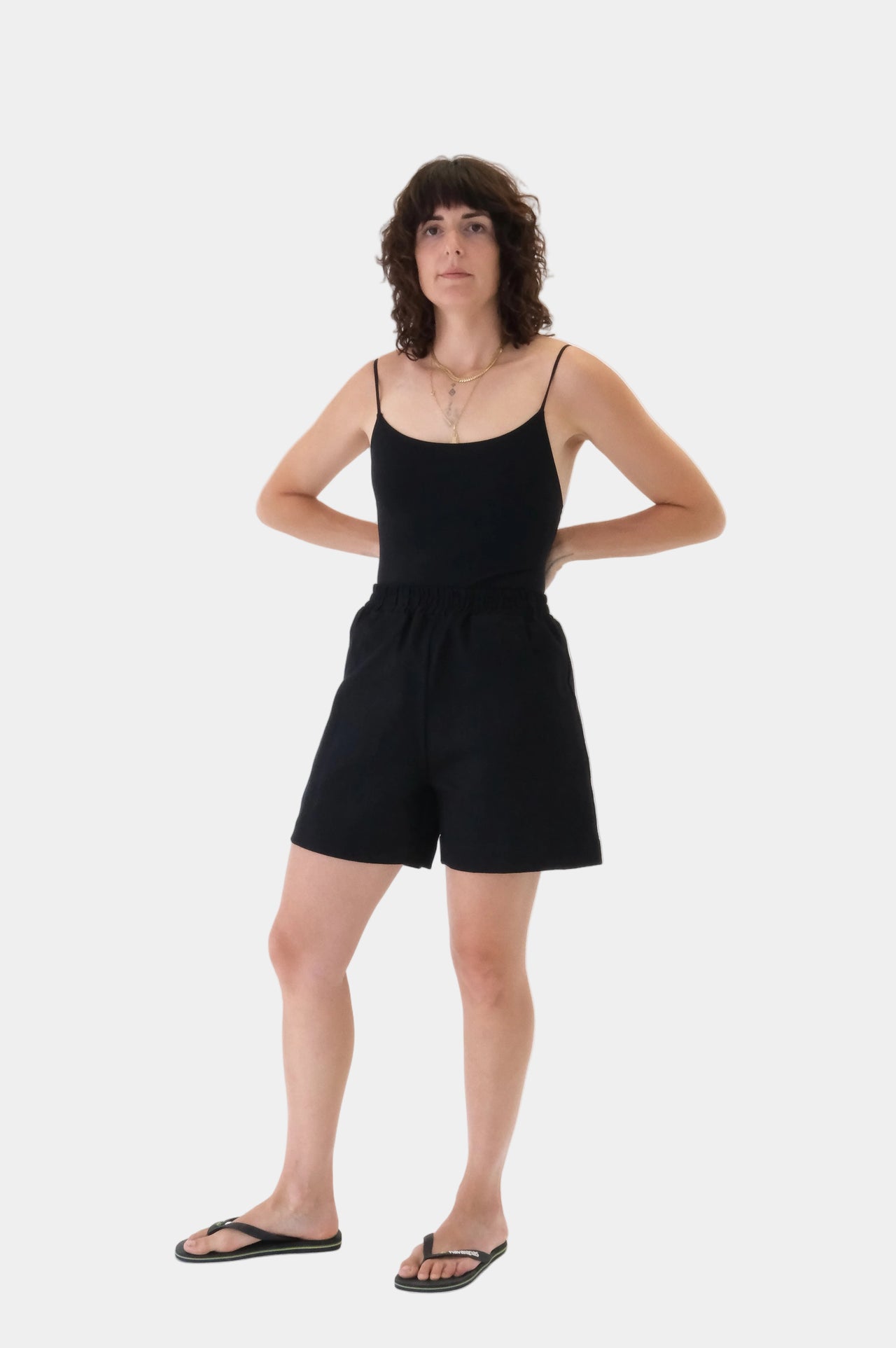 Person wearing a black sleeveless top and shorts on a white background