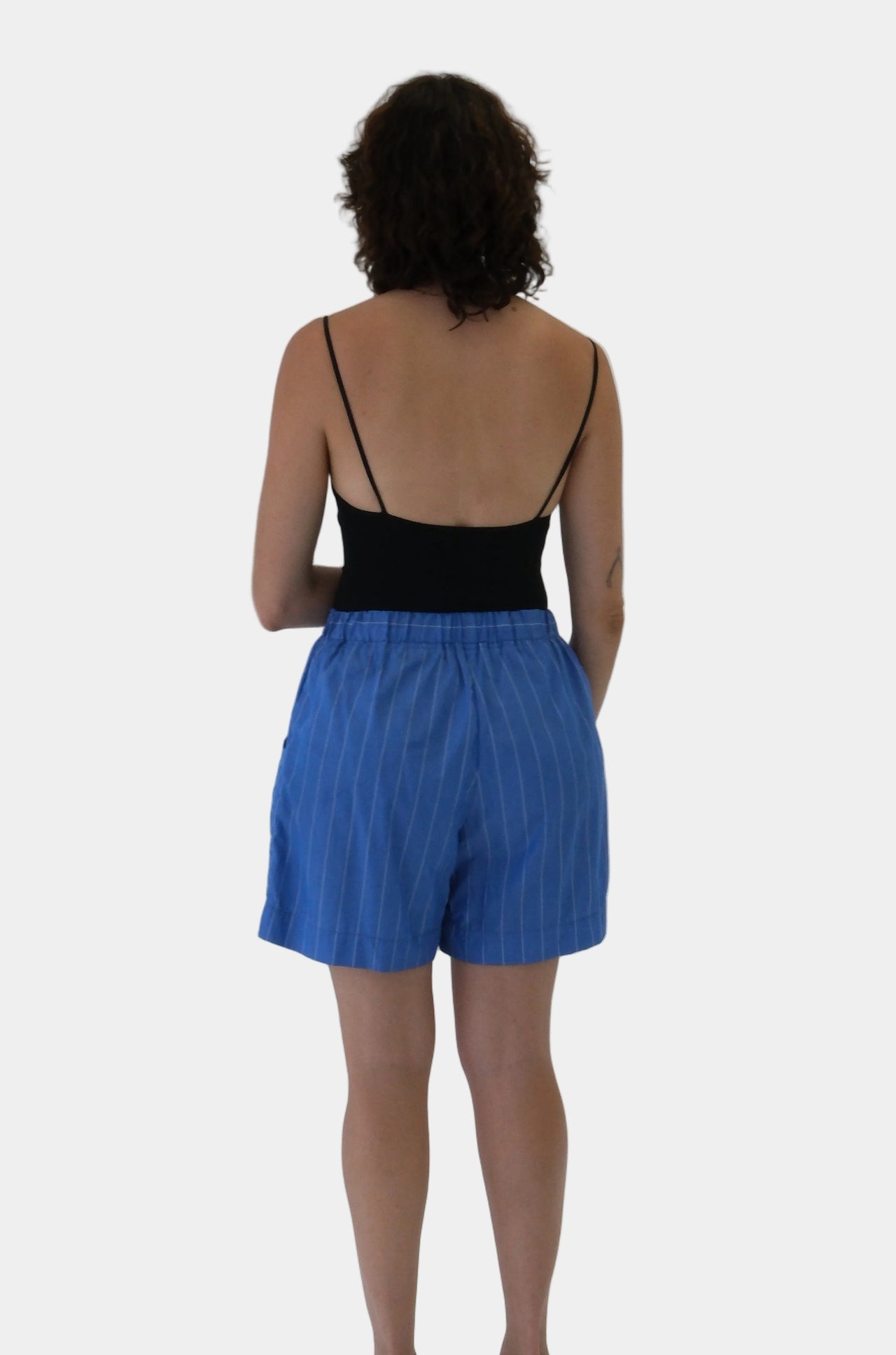 Woman wearing a black top and blue shorts on a white background