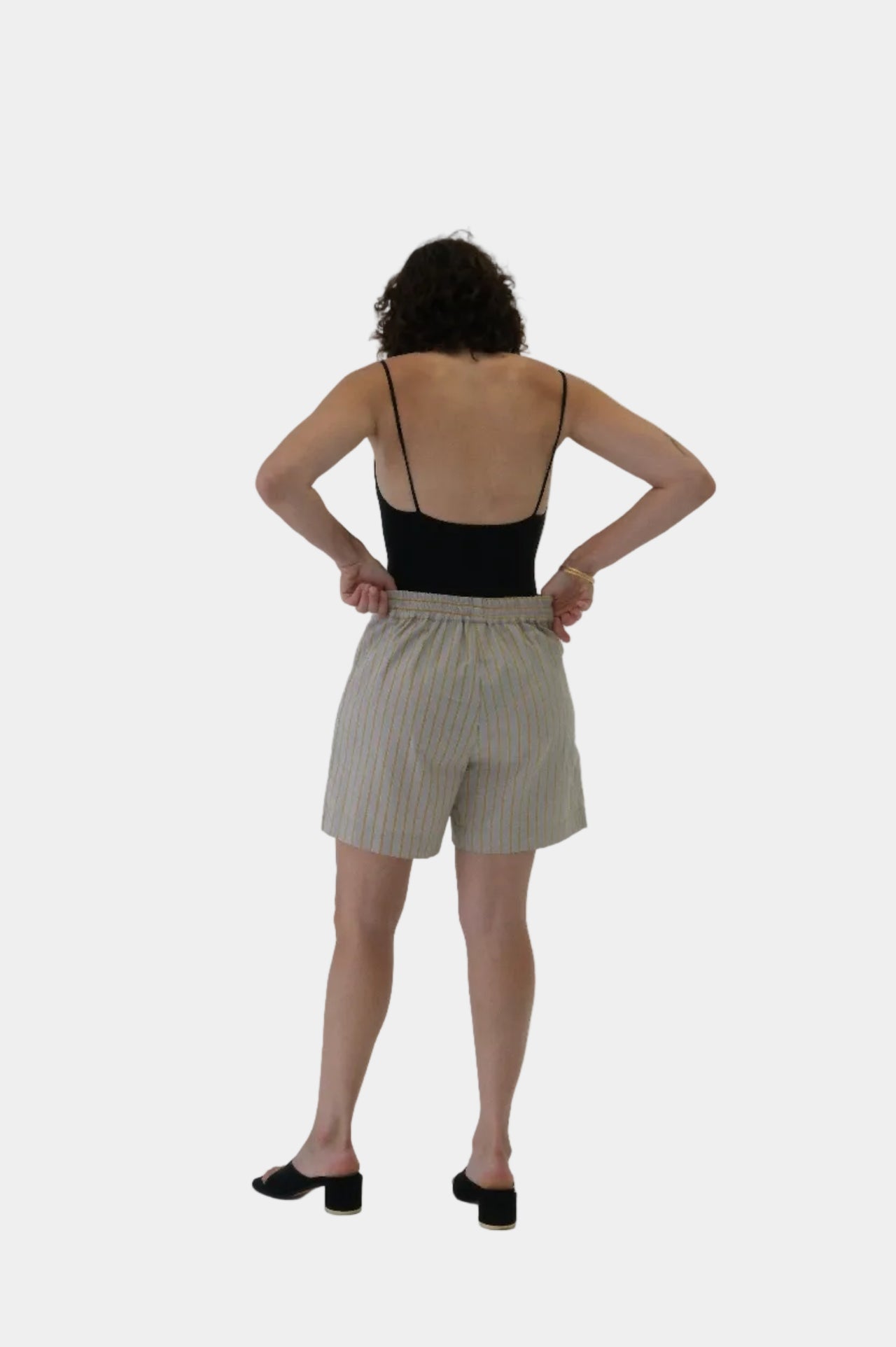 Woman wearing a black tank top and beige shorts on a white background