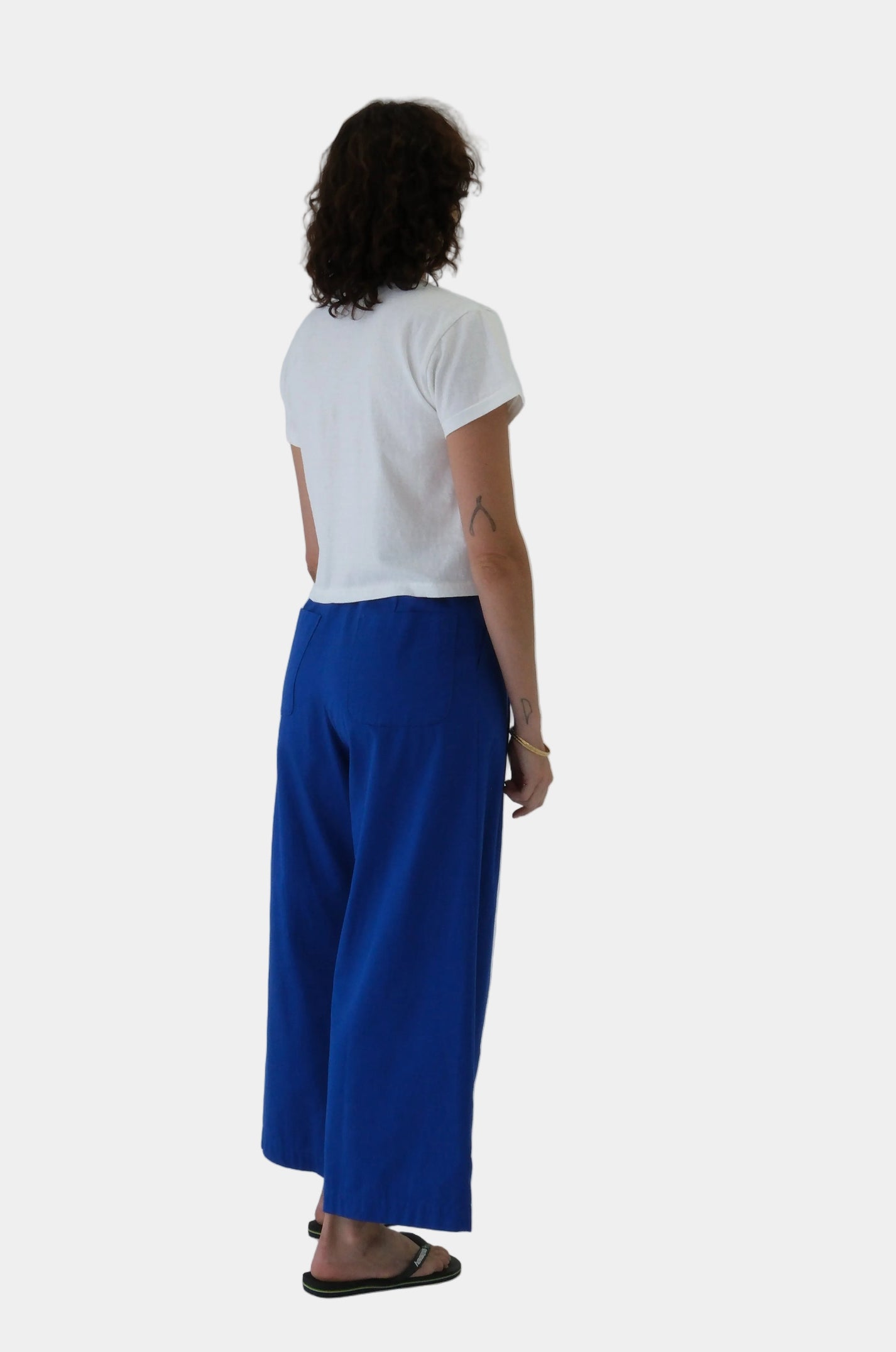 Person wearing a white shirt and blue pants on a plain background