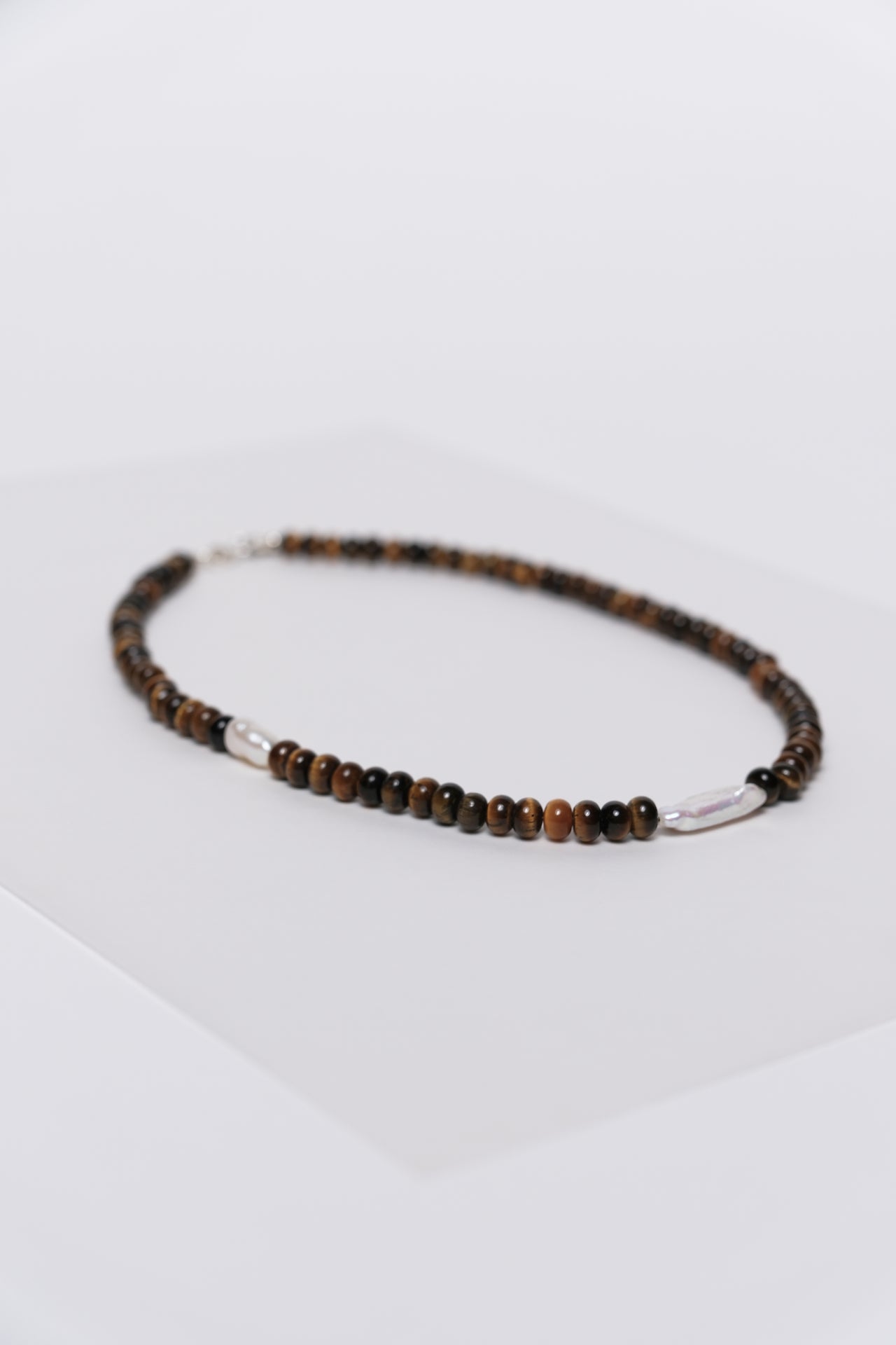 Tiger eye and freshwater pearl necklace displayed on a white background