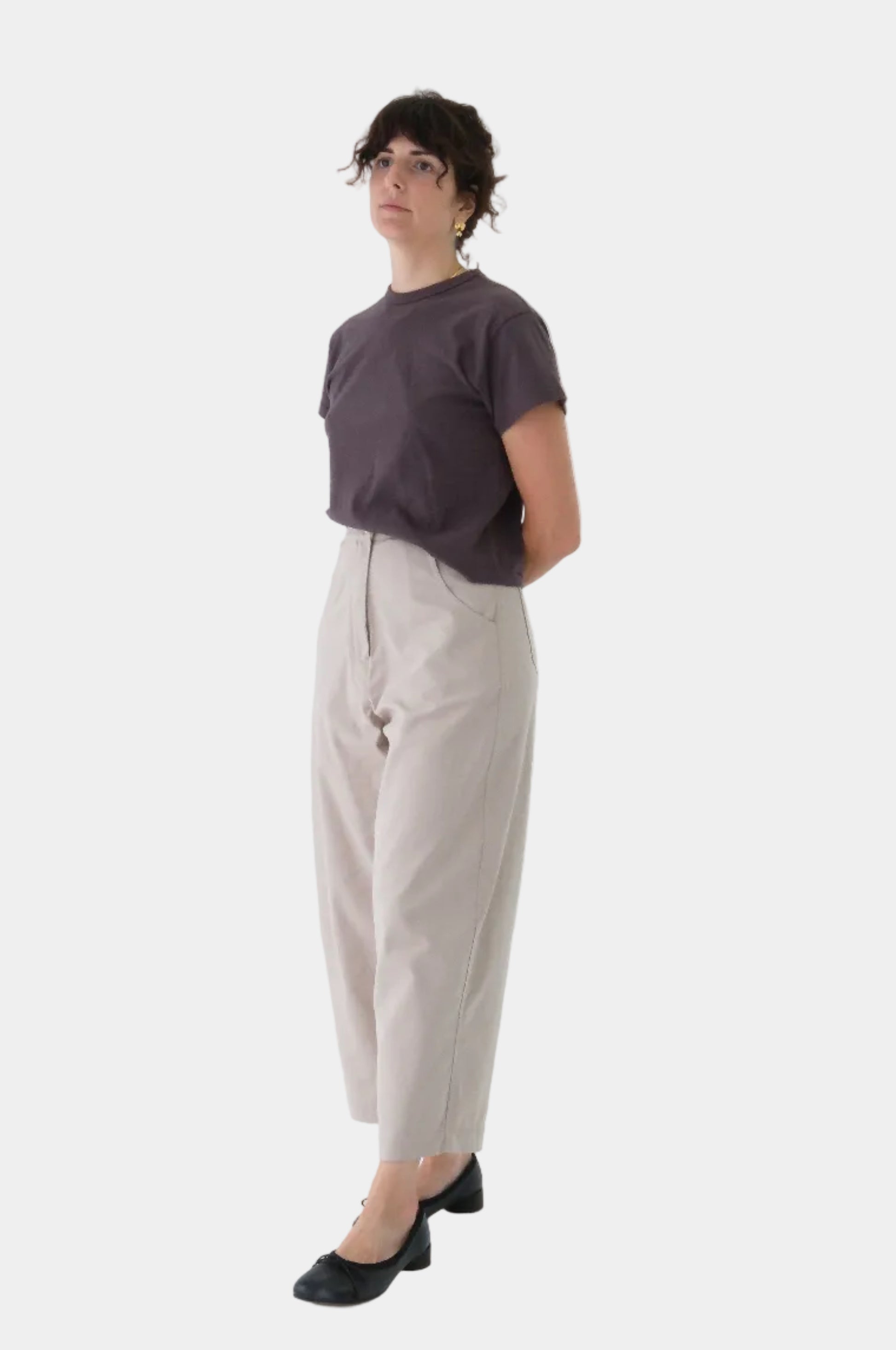 Person wearing a brown t-shirt and beige pants on a white background