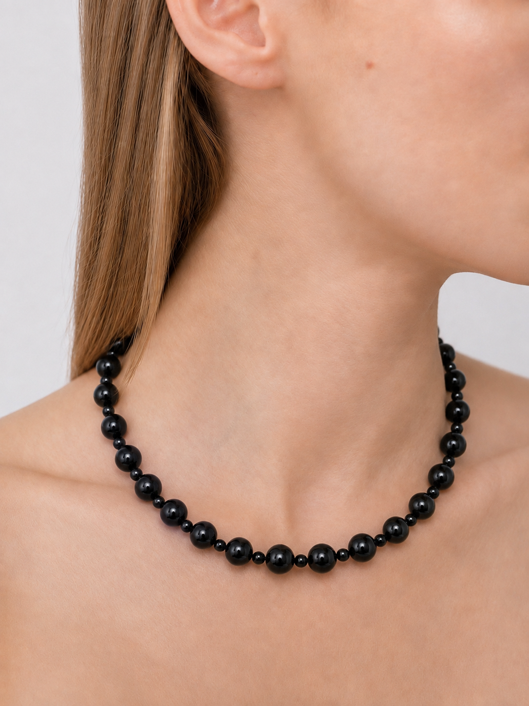 A close-up of a model wearing the No.4 black onyx beaded necklace with small spacer beads, shown against the neck and shoulders - East Coast General