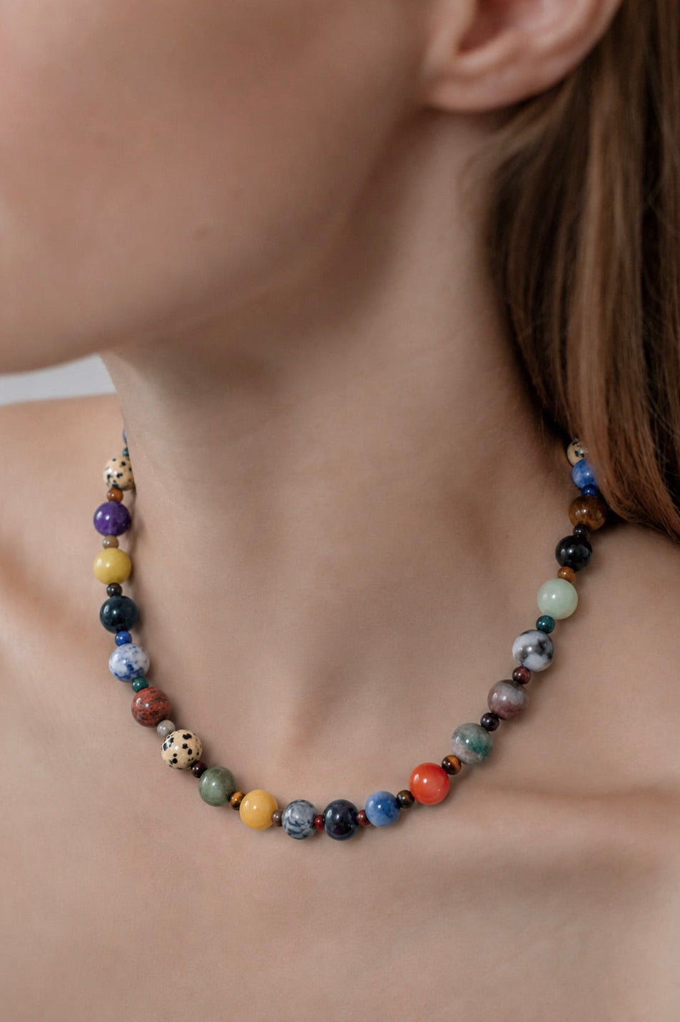 Multicolored beaded necklace on a person's neck with a blurred background