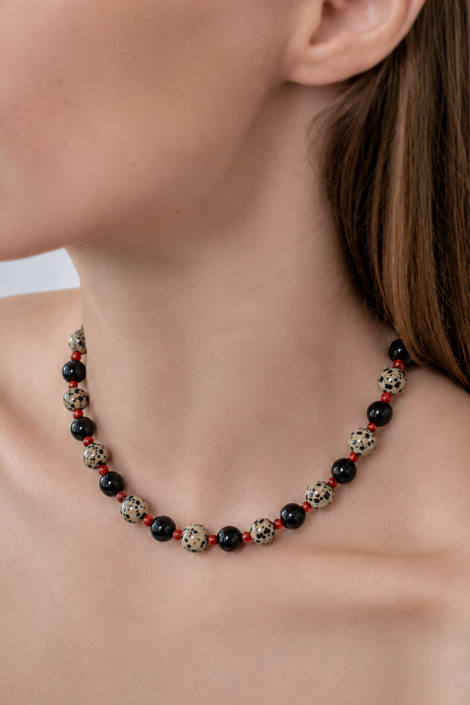 Necklace with black onyx and jasper beads on a persons neck close up