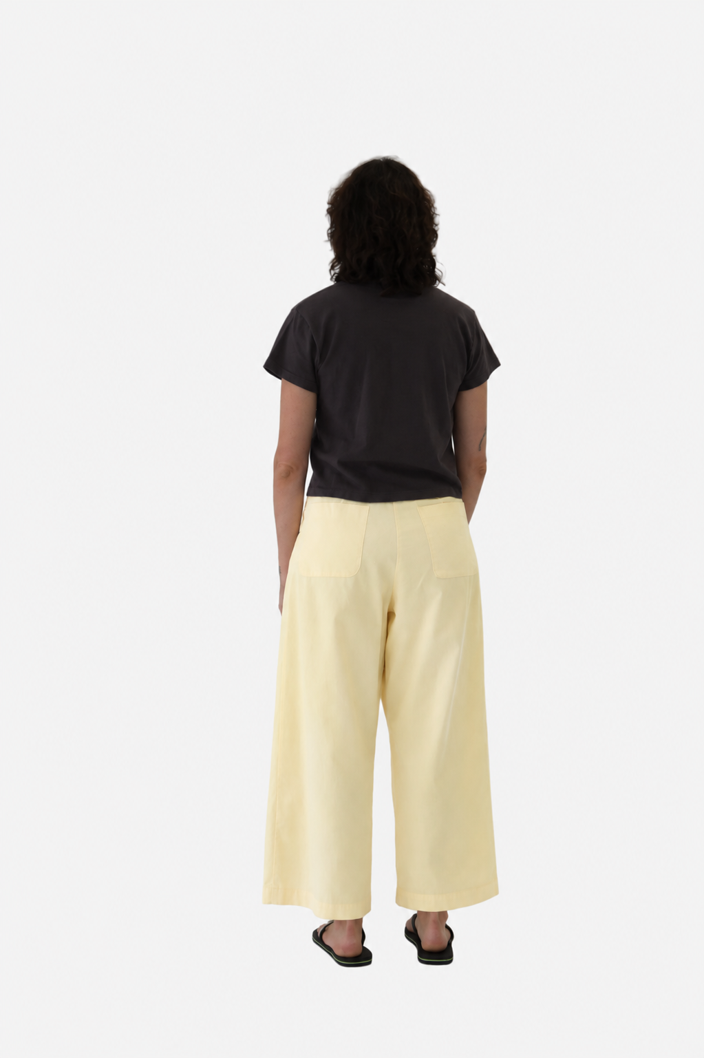 A  women wearing No. 53 pants in butter with Sunray hiaka tshirt in raisin, viewed from the back - East Coast General 