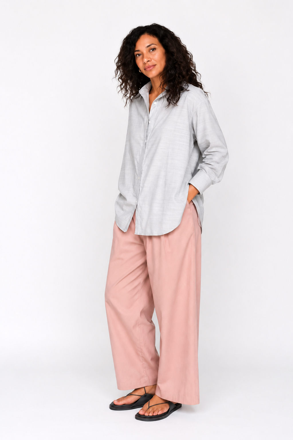 Woman wearing a light gray shirt and pink pants on a white background