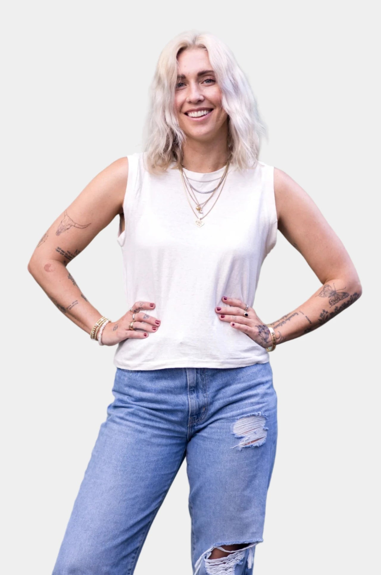 Woman wearing a white tank top and mustard yellow pants against a beige background