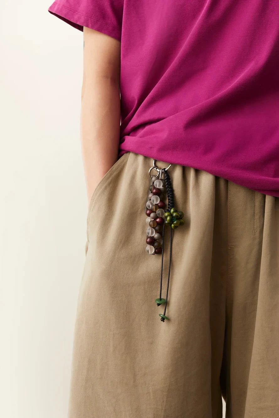 Person wearing a bright pink top and beige pants with a necklace, on a plain background