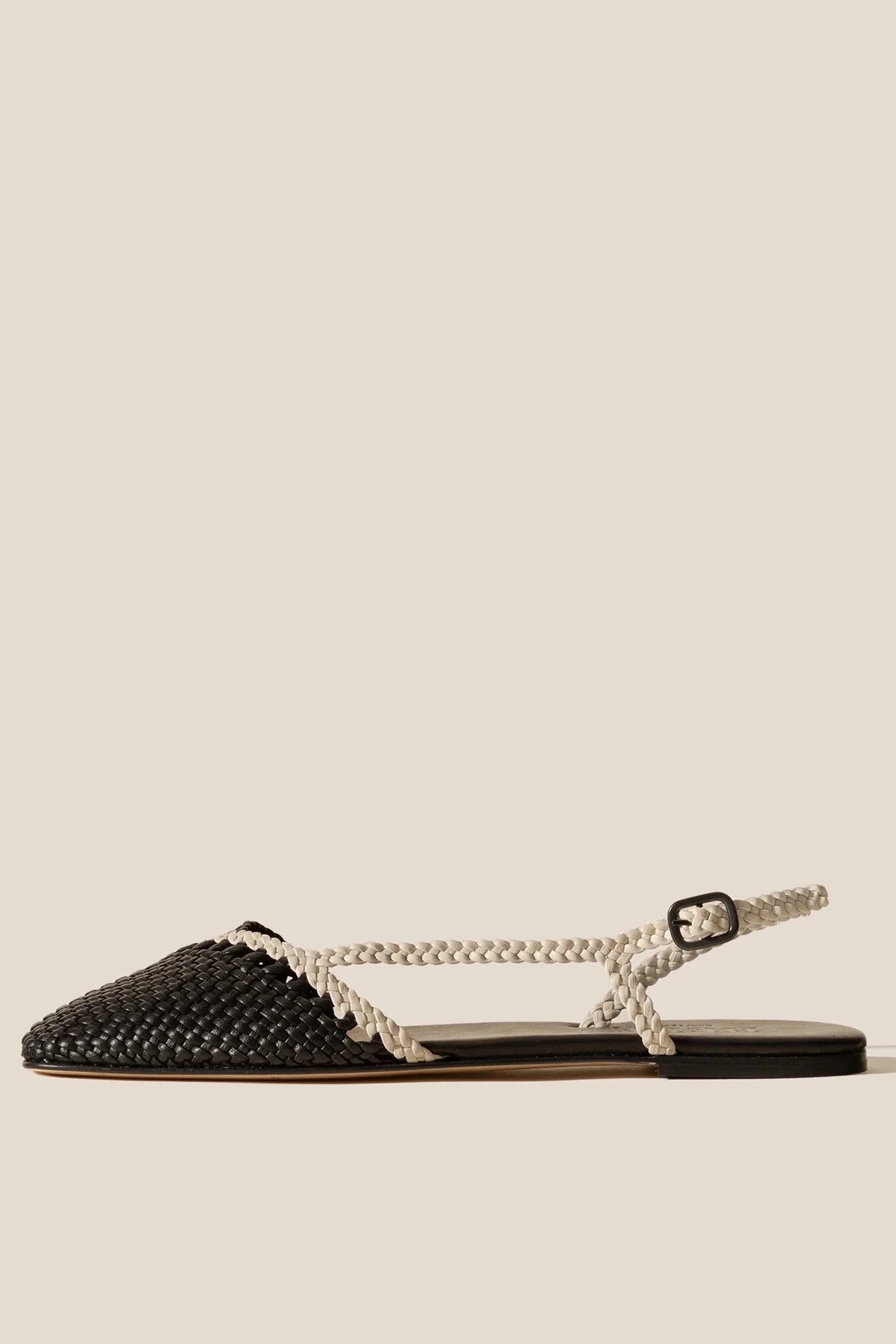Black woven sandal with a thin white strap on a beige background