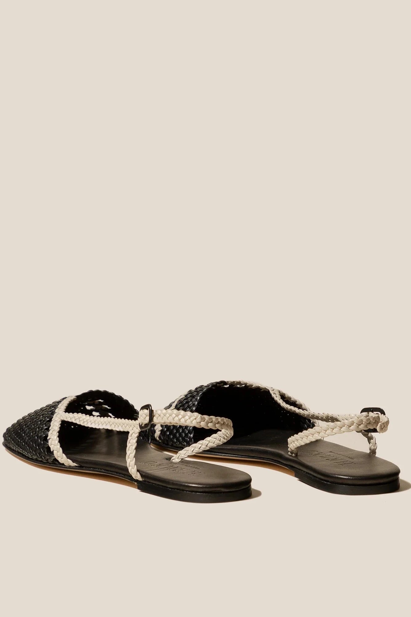 Pair of black sandals with white straps on a beige background