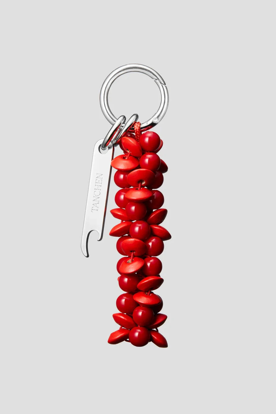 Red keychain with a metal bottle opener on a light gray background