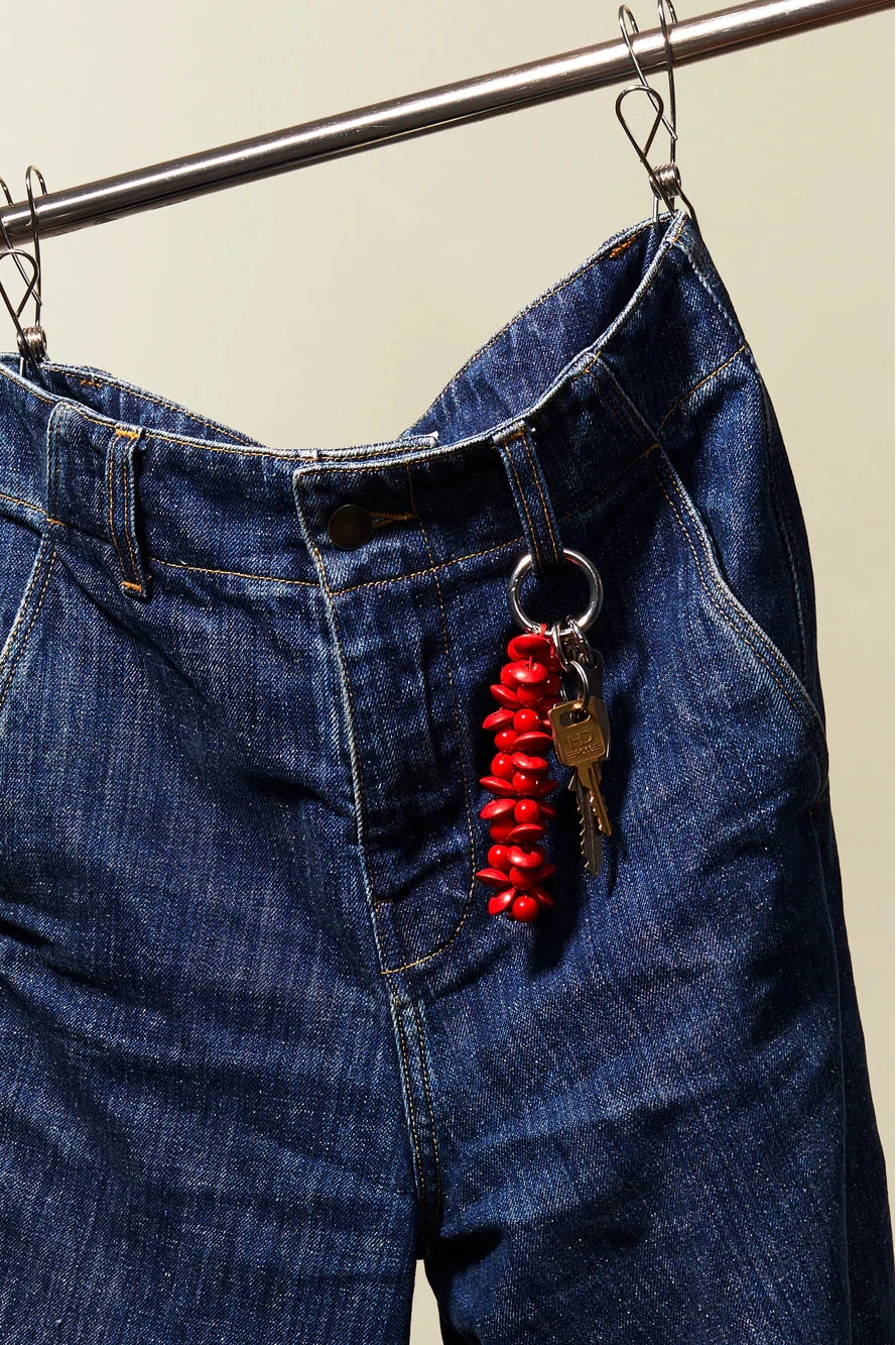 Blue jeans with a key and red object hanging from the pocket on a beige background