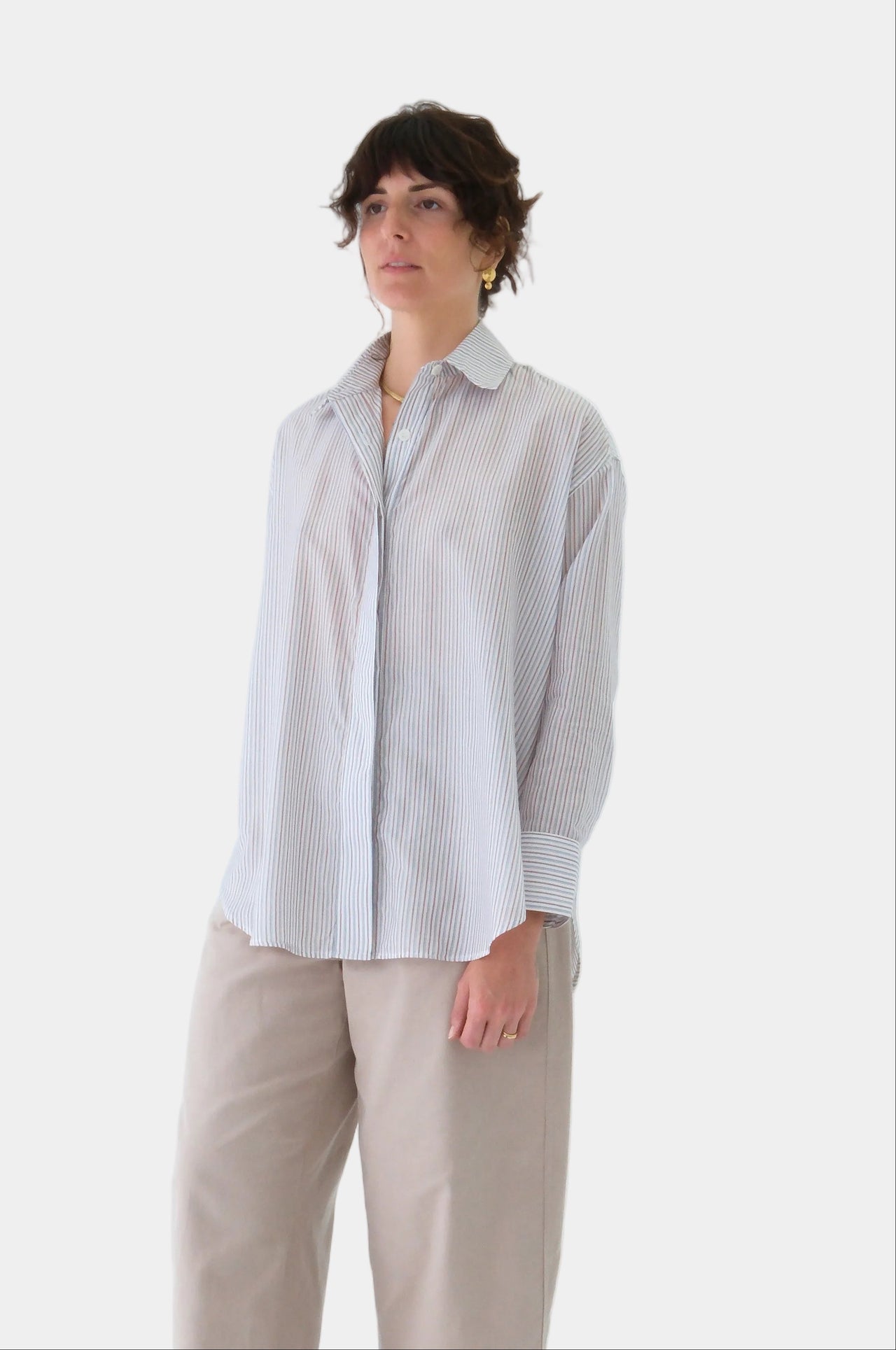 Person wearing a striped shirt with rolled-up sleeves on a light gray background