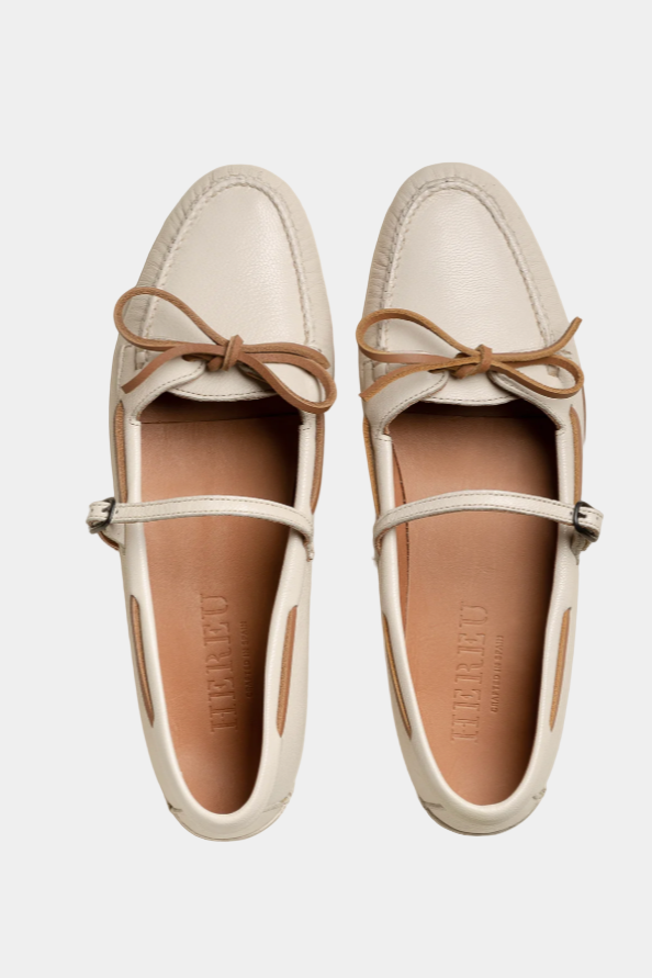 Pair of white loafers with brown bows on a white background