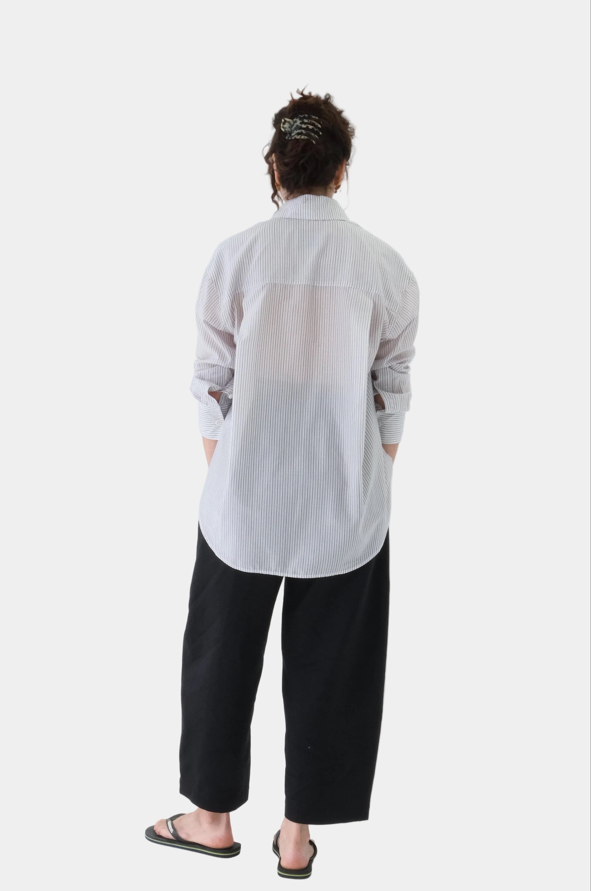 Person wearing a light gray cardigan and black pants on a white background