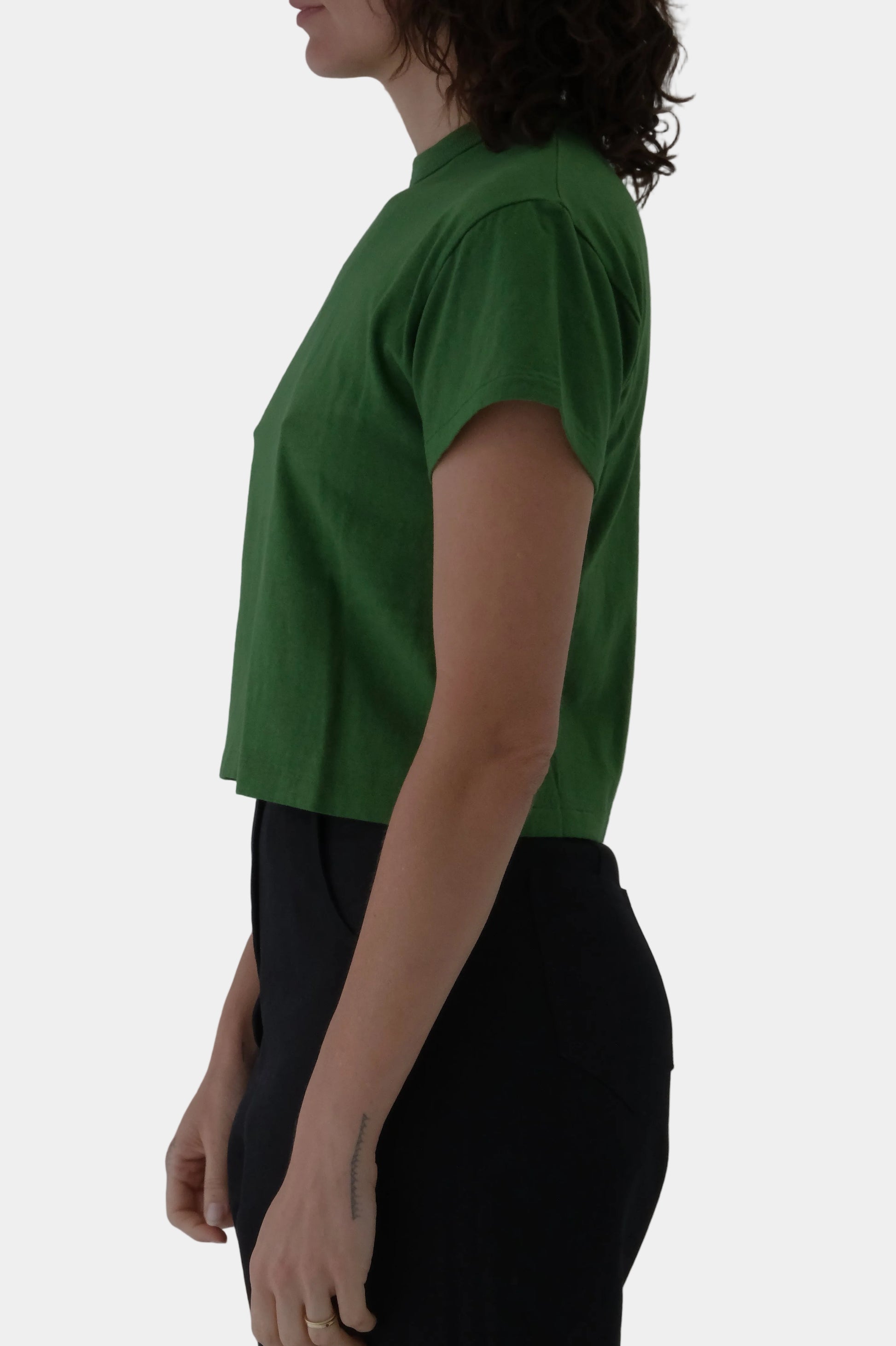 Person wearing a green top and black pants on a white background