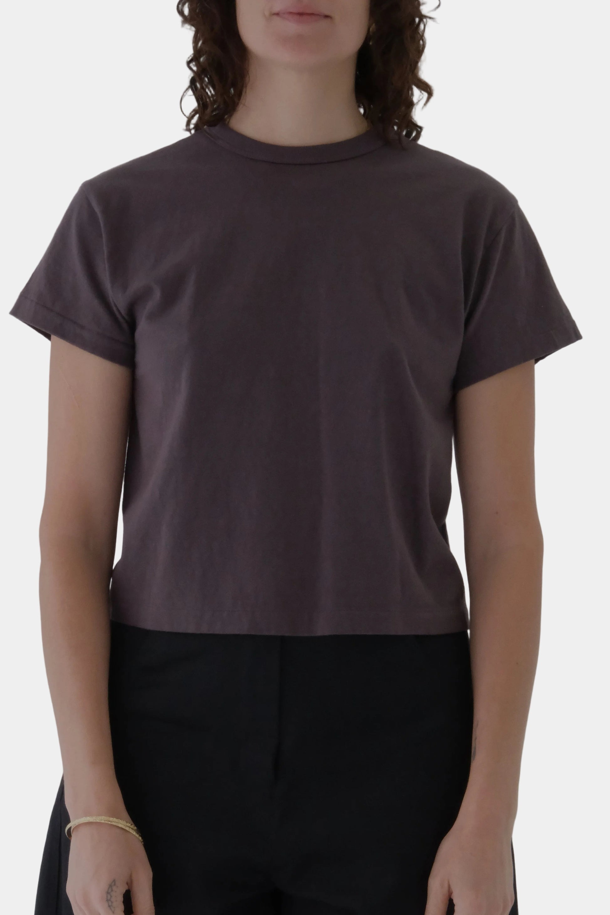 Person wearing a plain brown t-shirt against a gray background