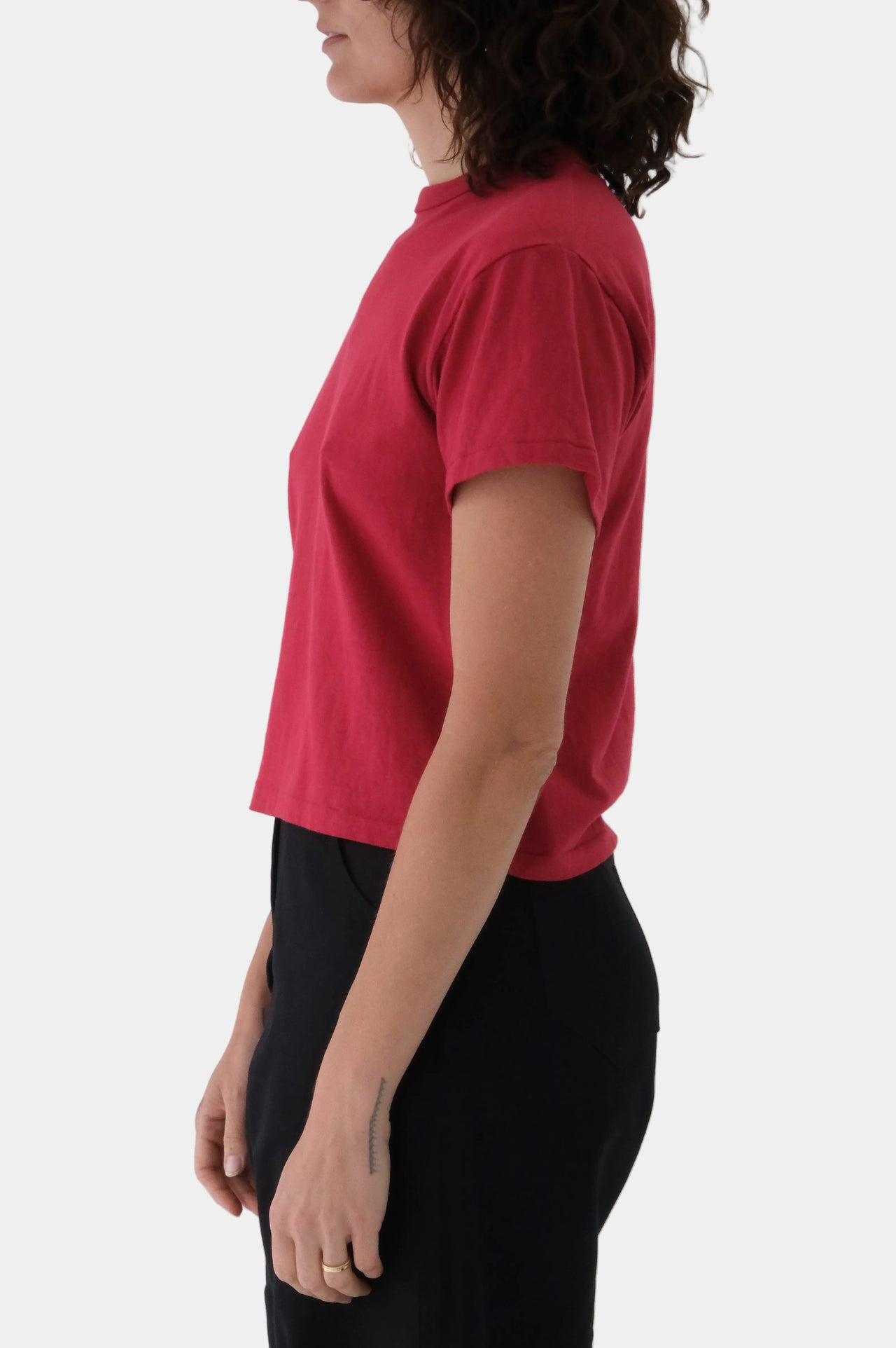 Person wearing a red t-shirt and black pants on a gray background
