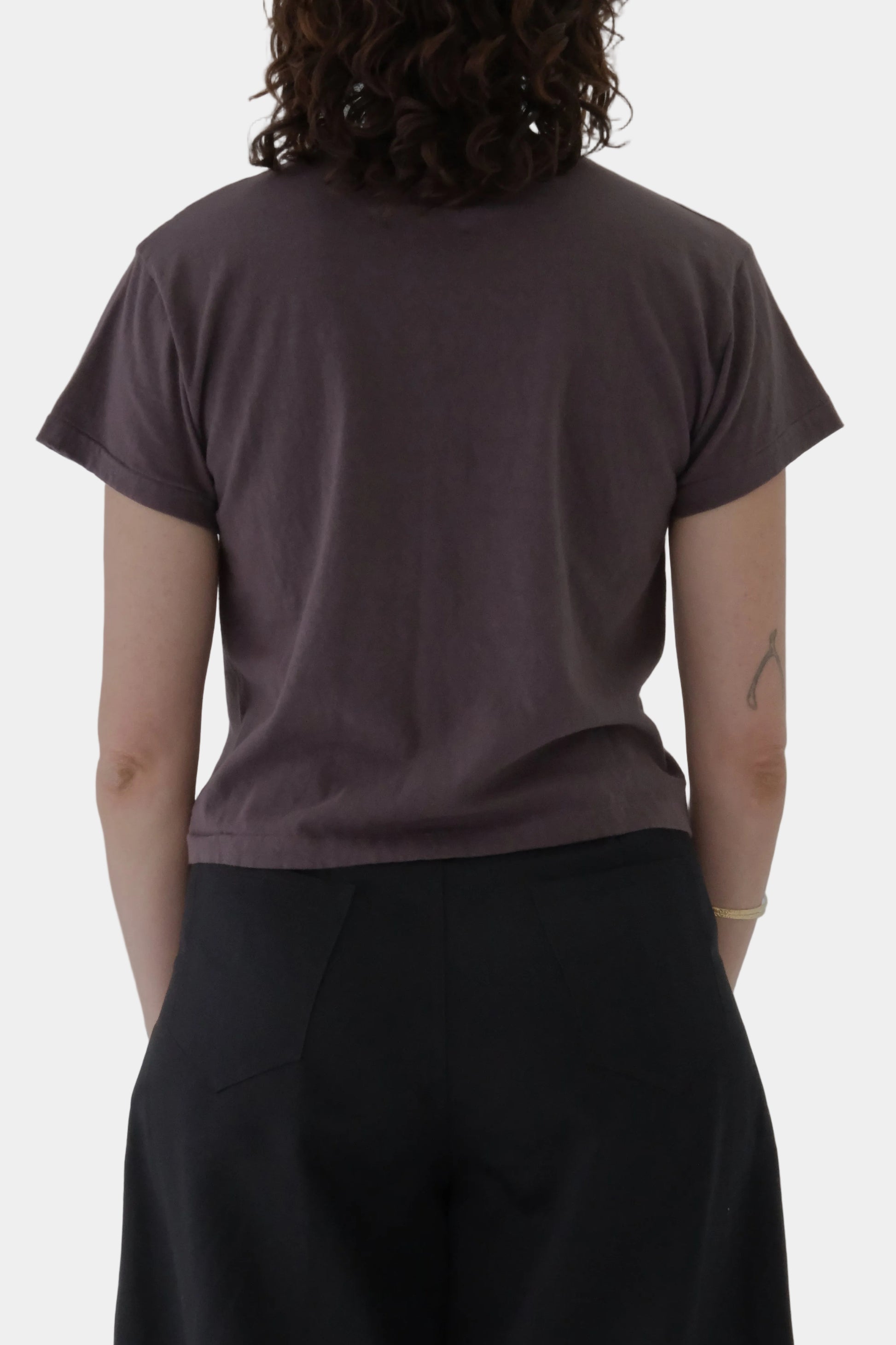 Person wearing a brown t-shirt and black pants on a gray background