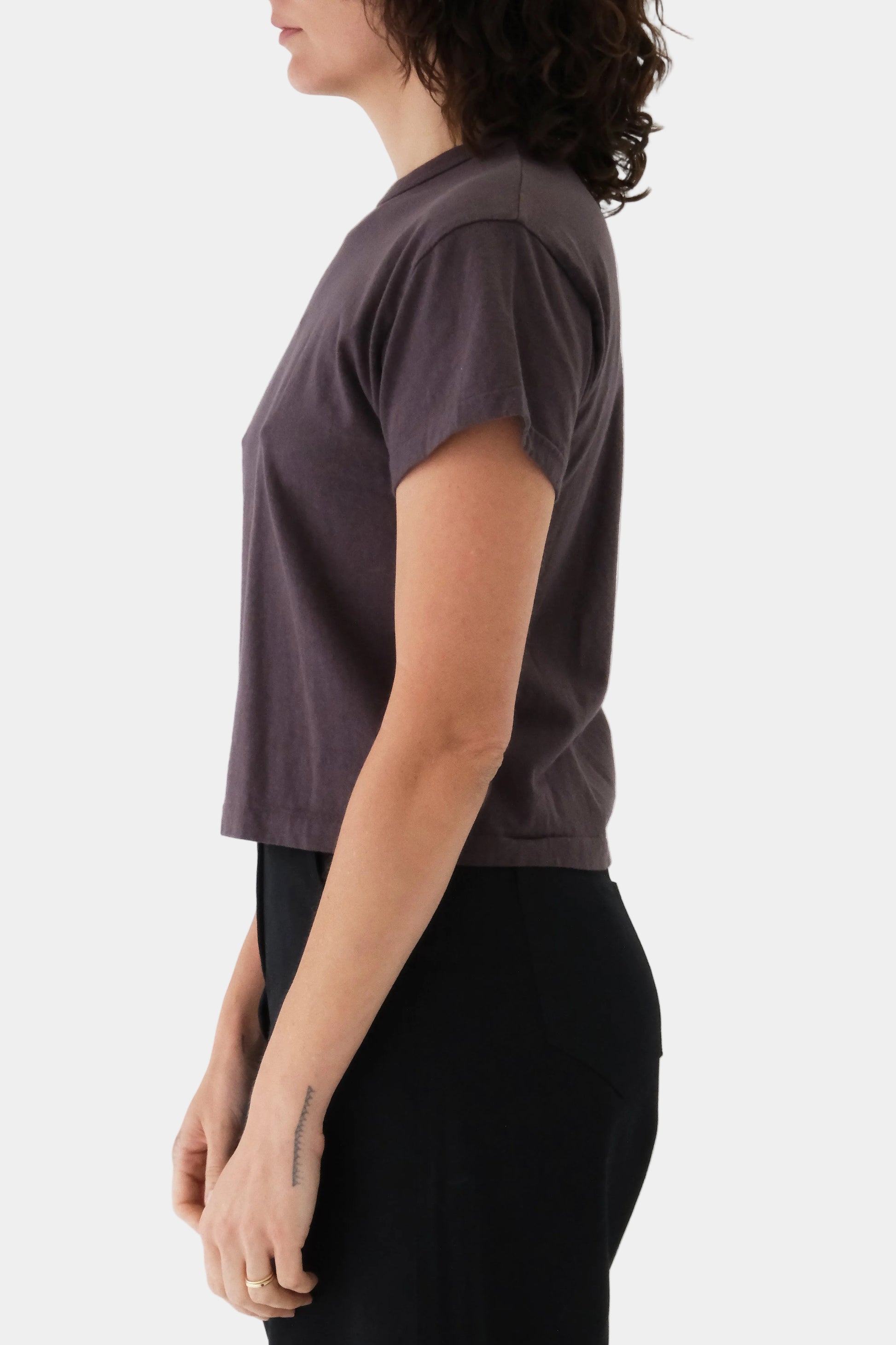 Person wearing a dark gray t-shirt and black pants on a light gray background