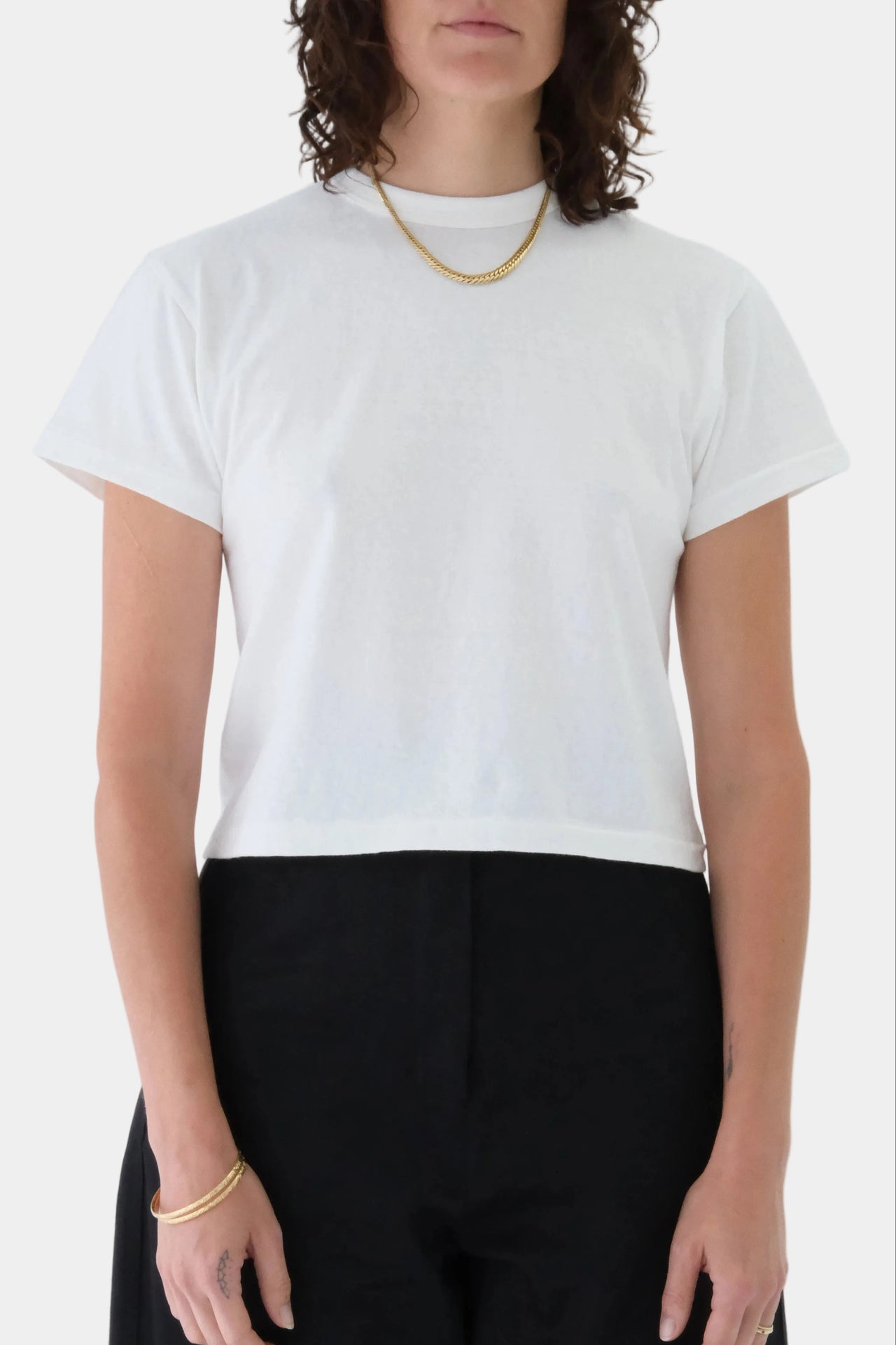 Person wearing a white t-shirt and black pants on a plain background