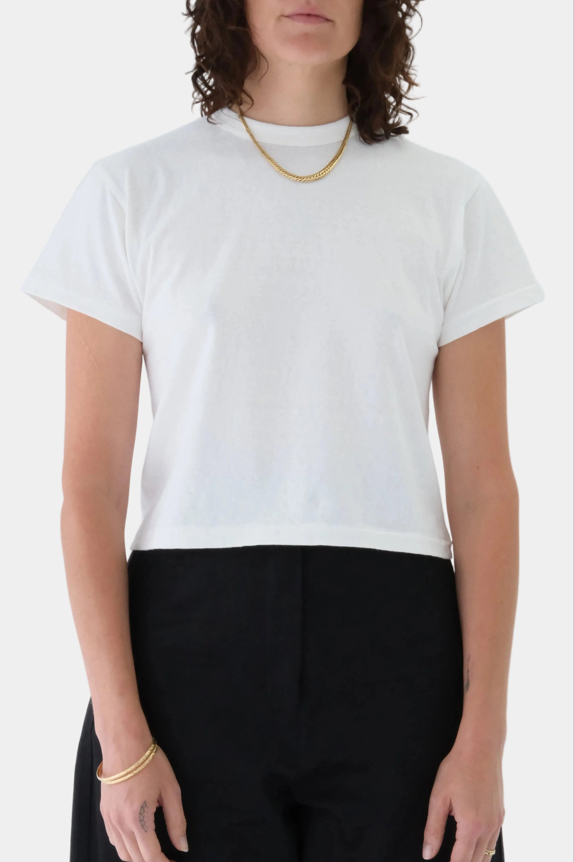 Person wearing a white t-shirt and black pants on a plain background