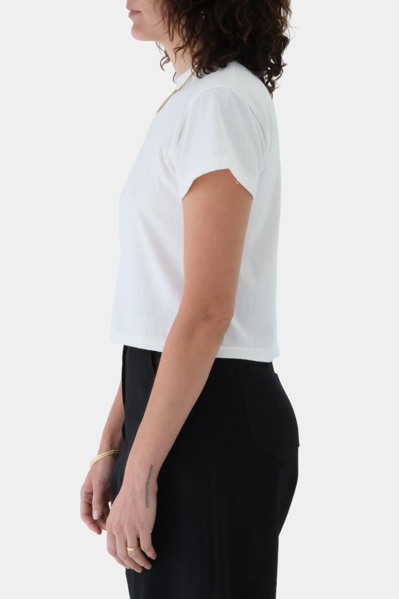 Person wearing a white t-shirt and black pants on a plain background