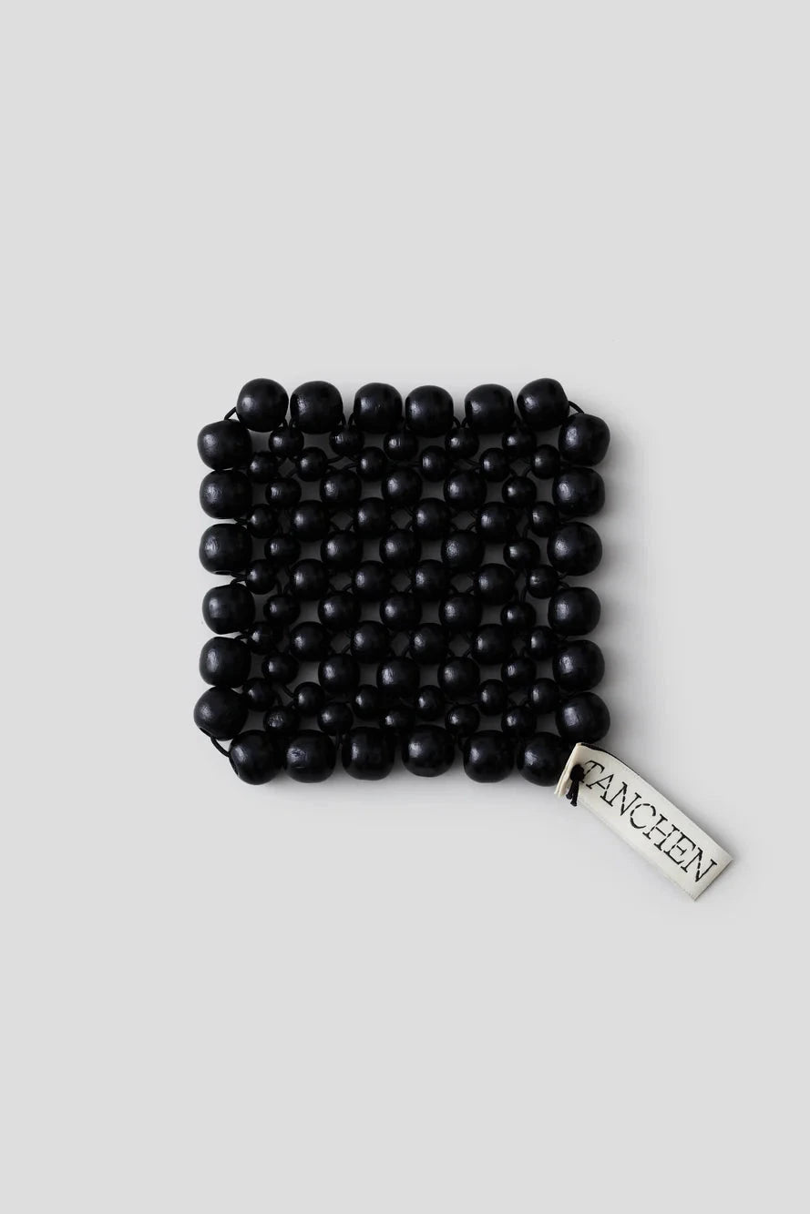Black beaded bracelet with a tag on a light gray background